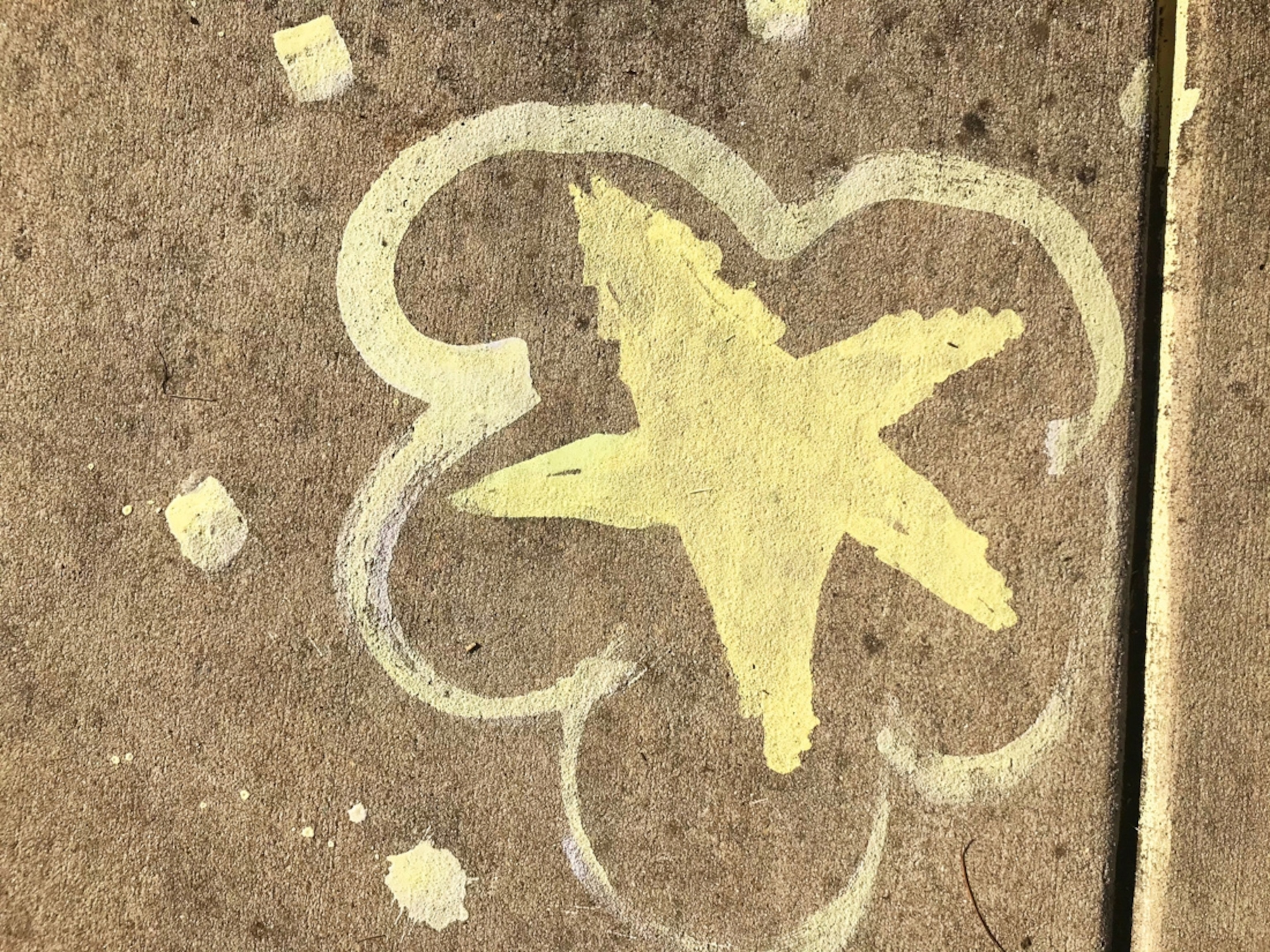 A yellow star on the sidewalk drawn with home-made chalk.