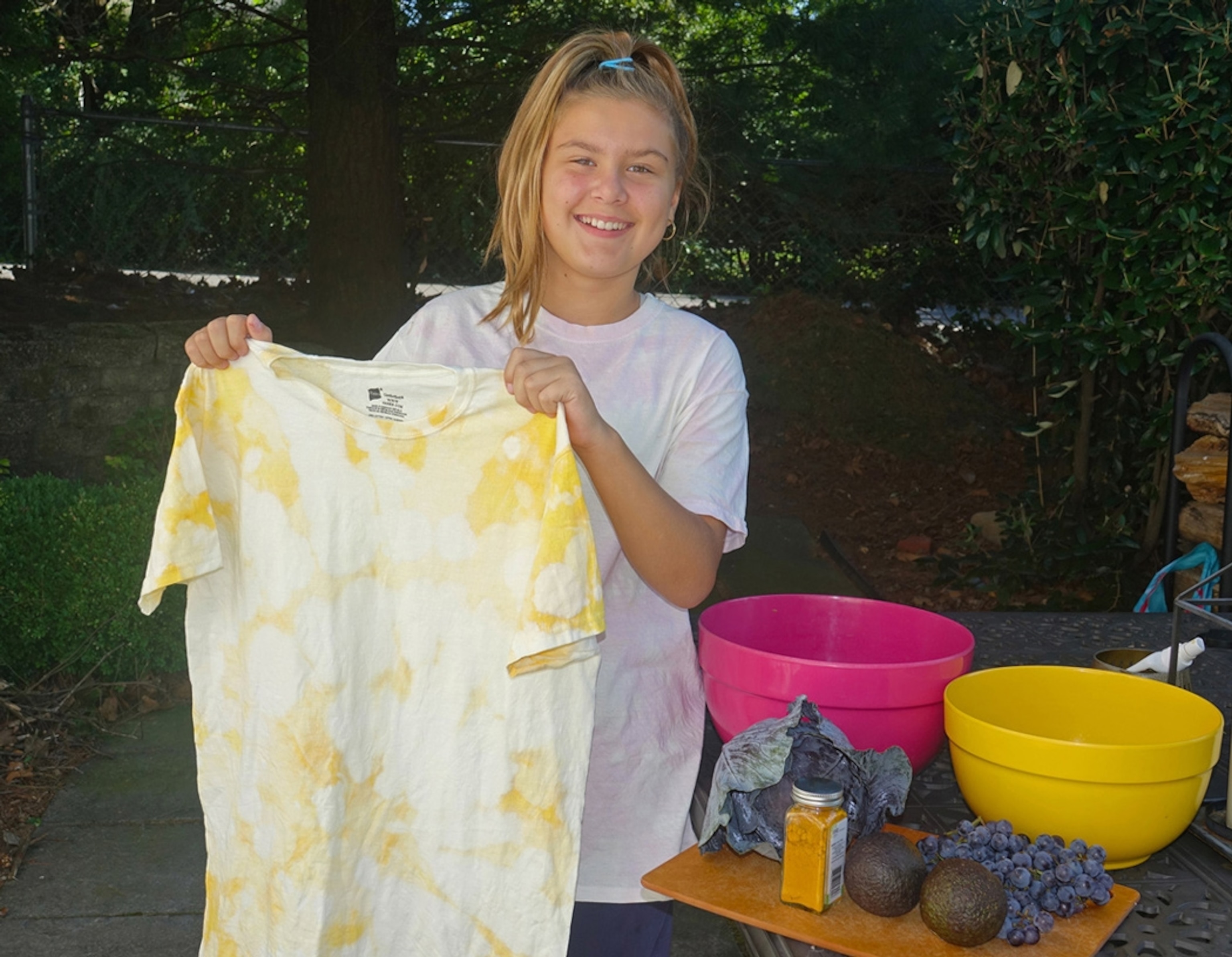 An 11 year-old girl holding a shirt tie-dyed with tumeric.