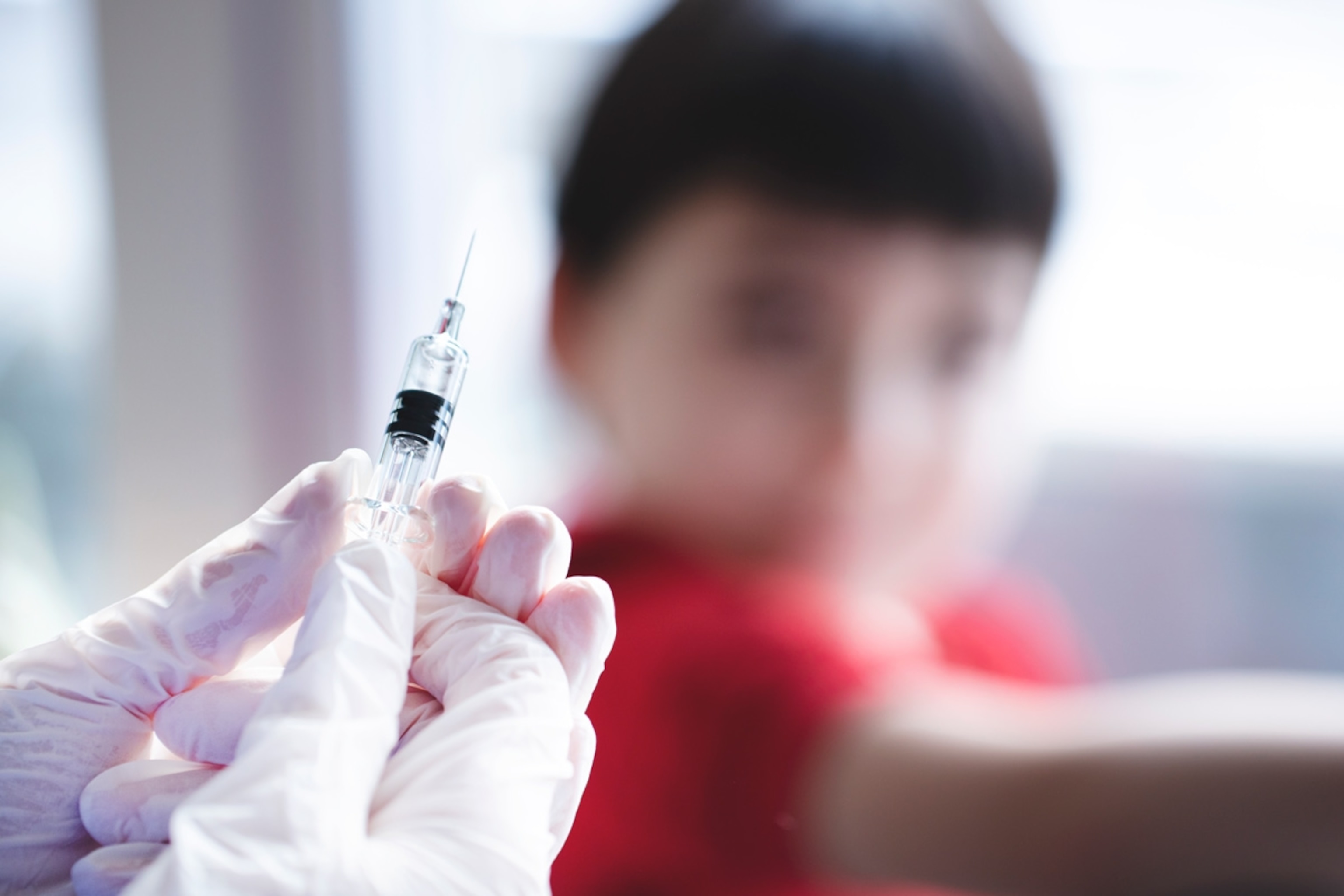 This picture depicts a young female clinician using a syringe to inject a COVD liquid vaccine.