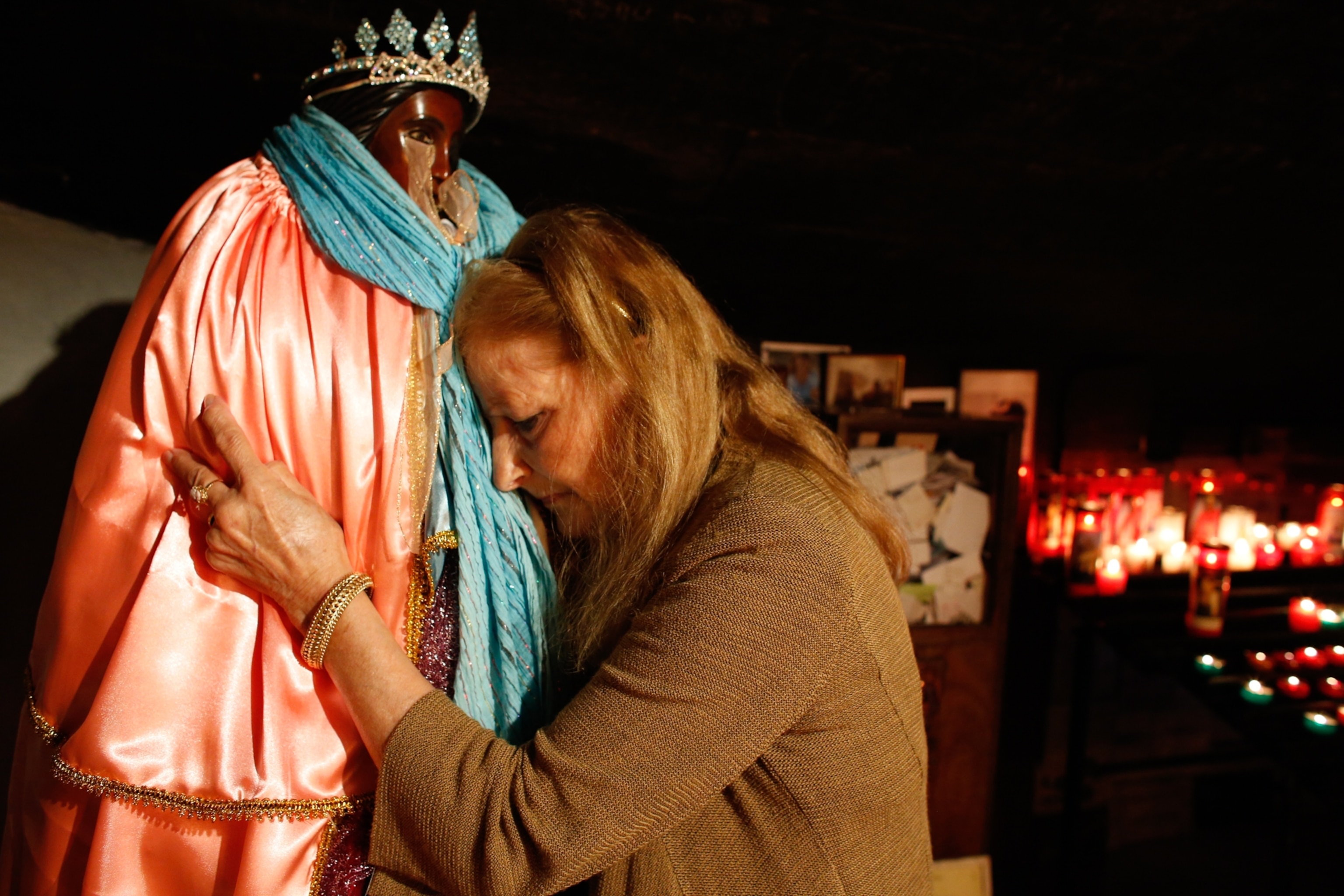 A Roma pilgrim embraces a statue of Santa Sara.