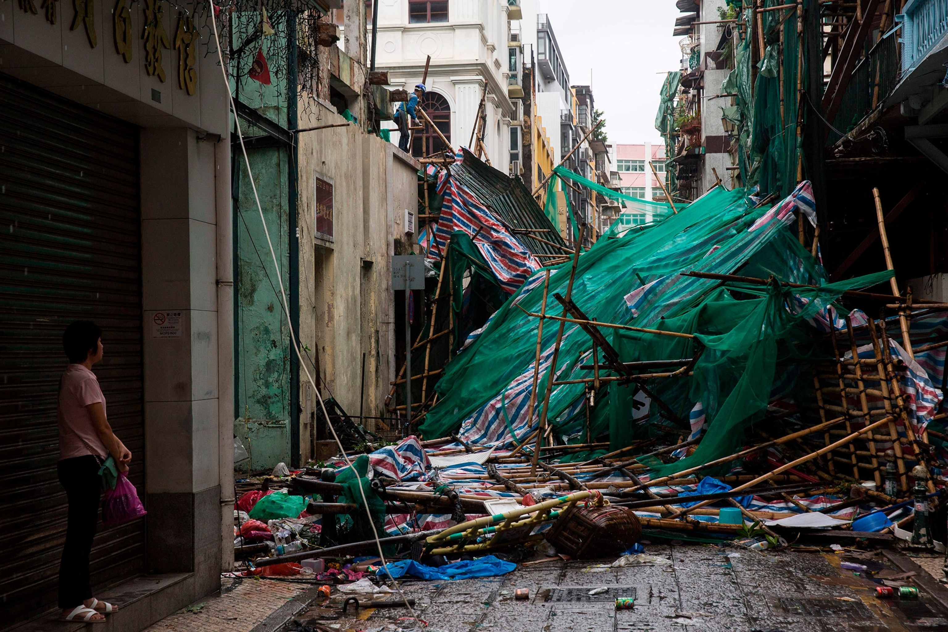 a woman staring ahead as a worked removes scaffolding