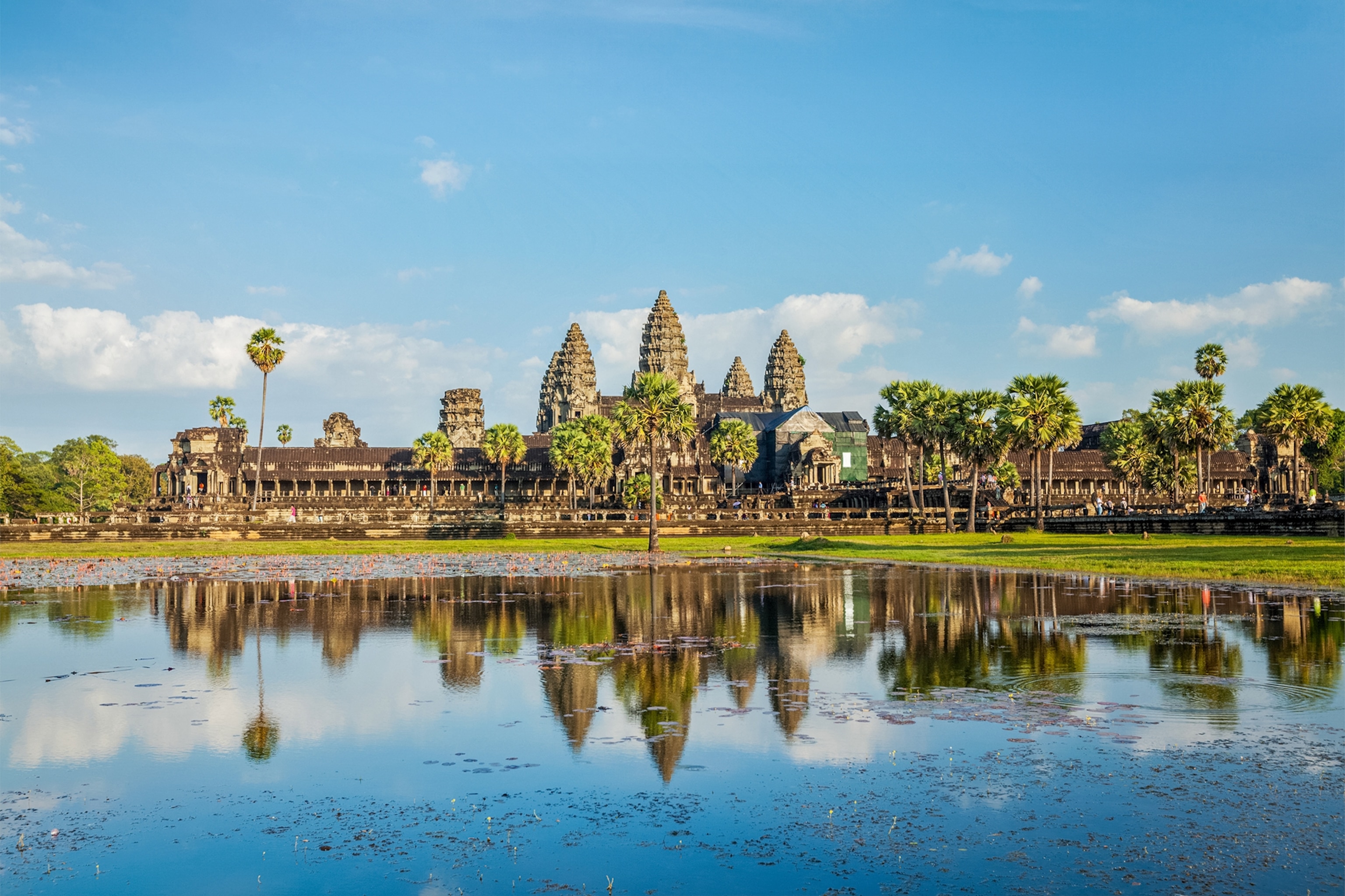 A far shot of Angkor Wat in Thailand. The building is reflected in a body of water.