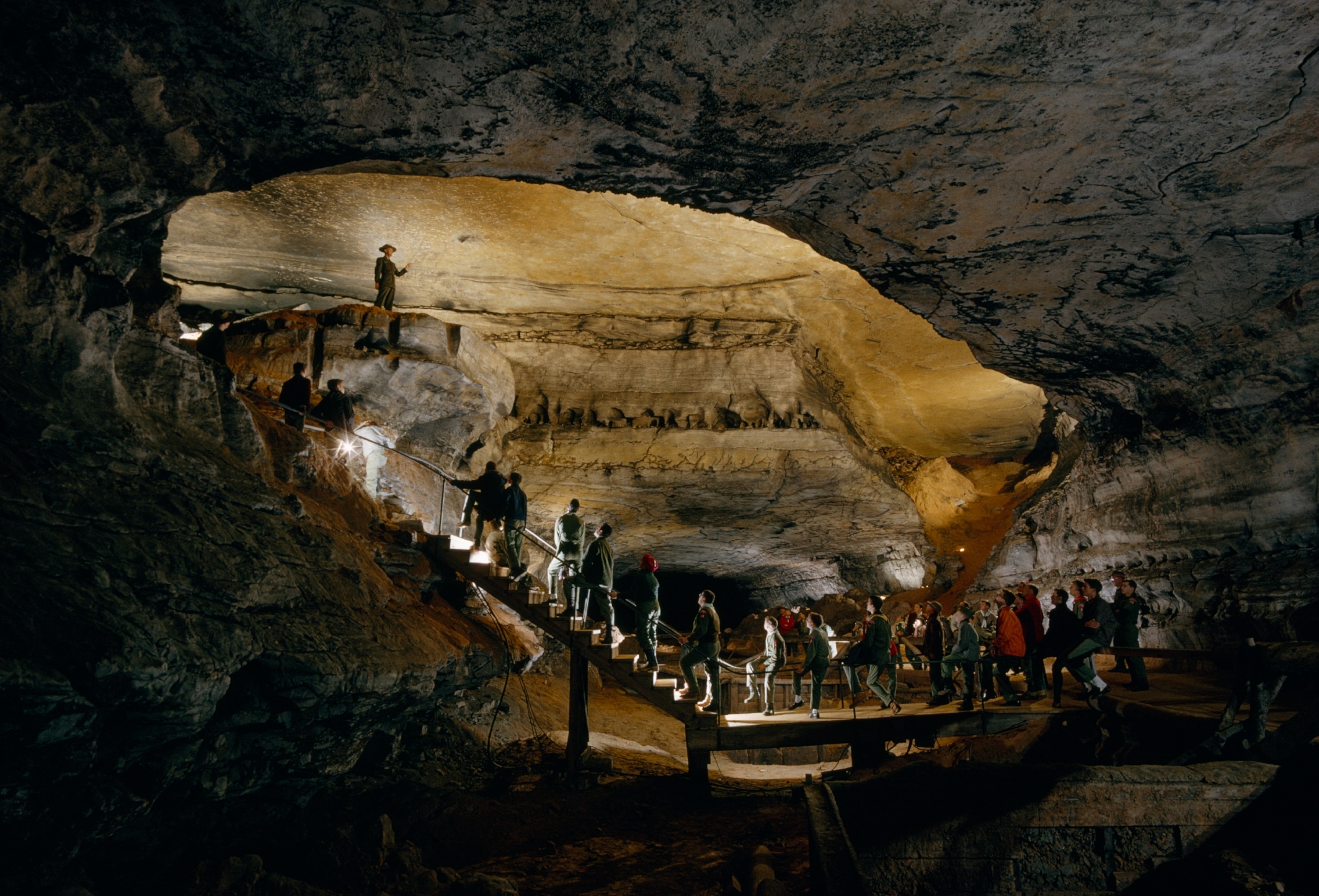 Boy scouts lined up on a staircase in a cave with a ranger