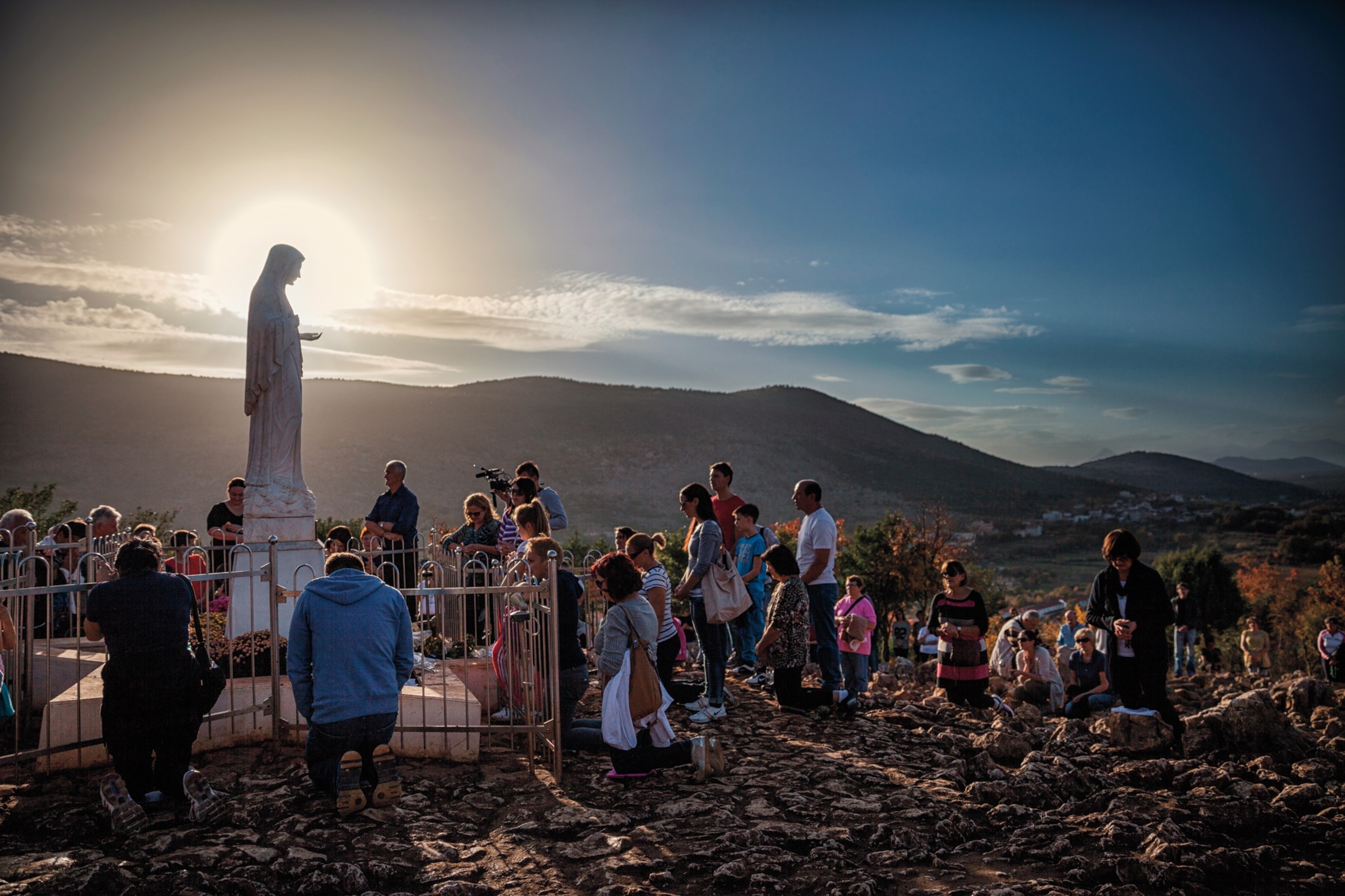Photo of Mary statue with crowd in front of it.