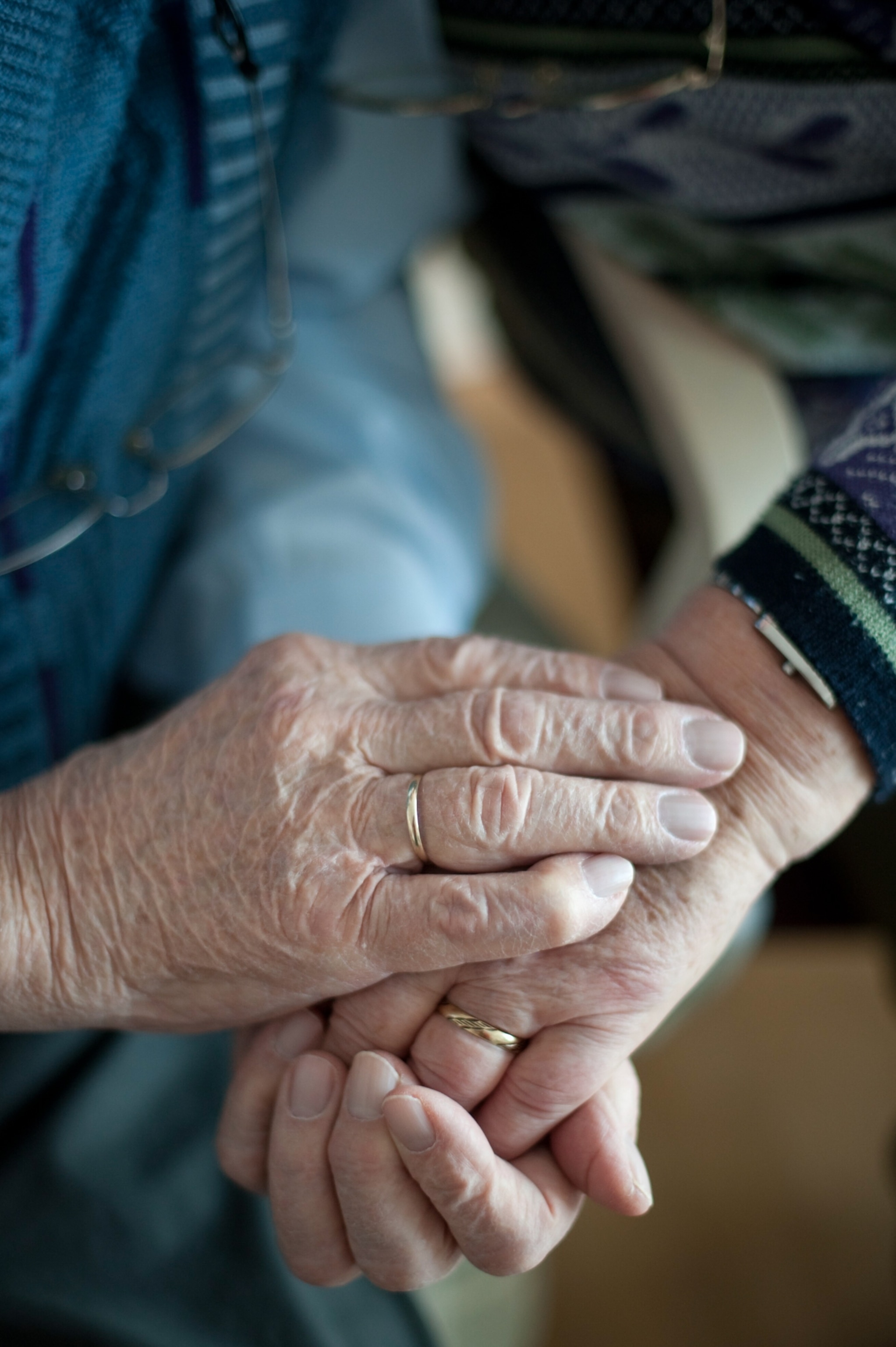 A close up view of an elderly couple holding hands.