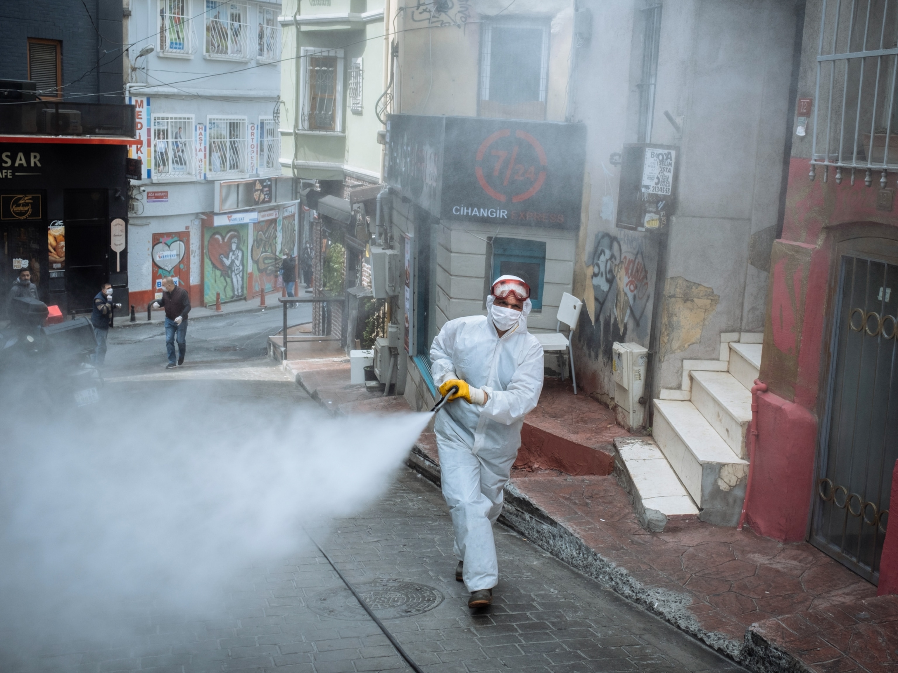 a person sprays disinfectant on thee street in Istanbul