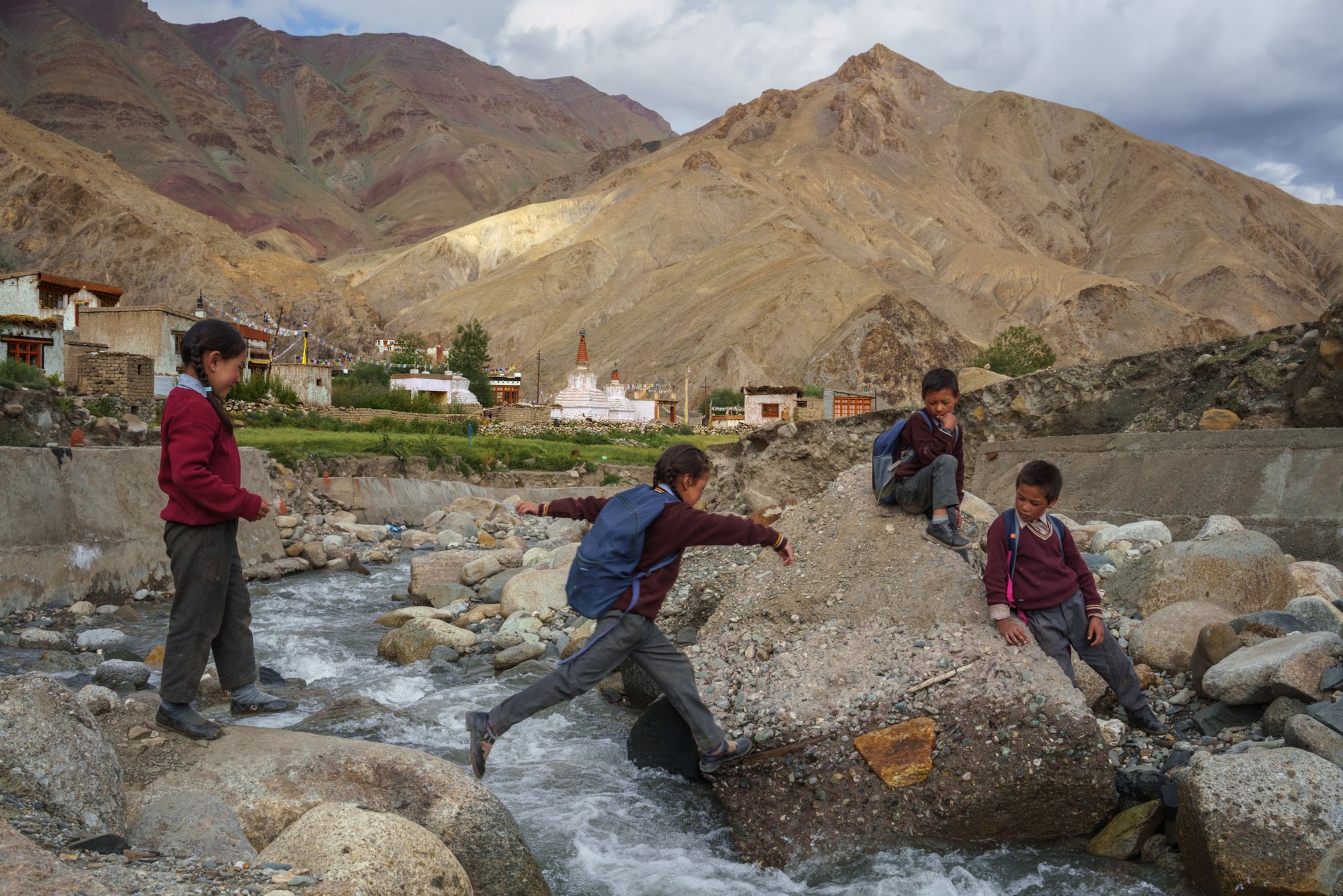 school children jumping over a narrow river