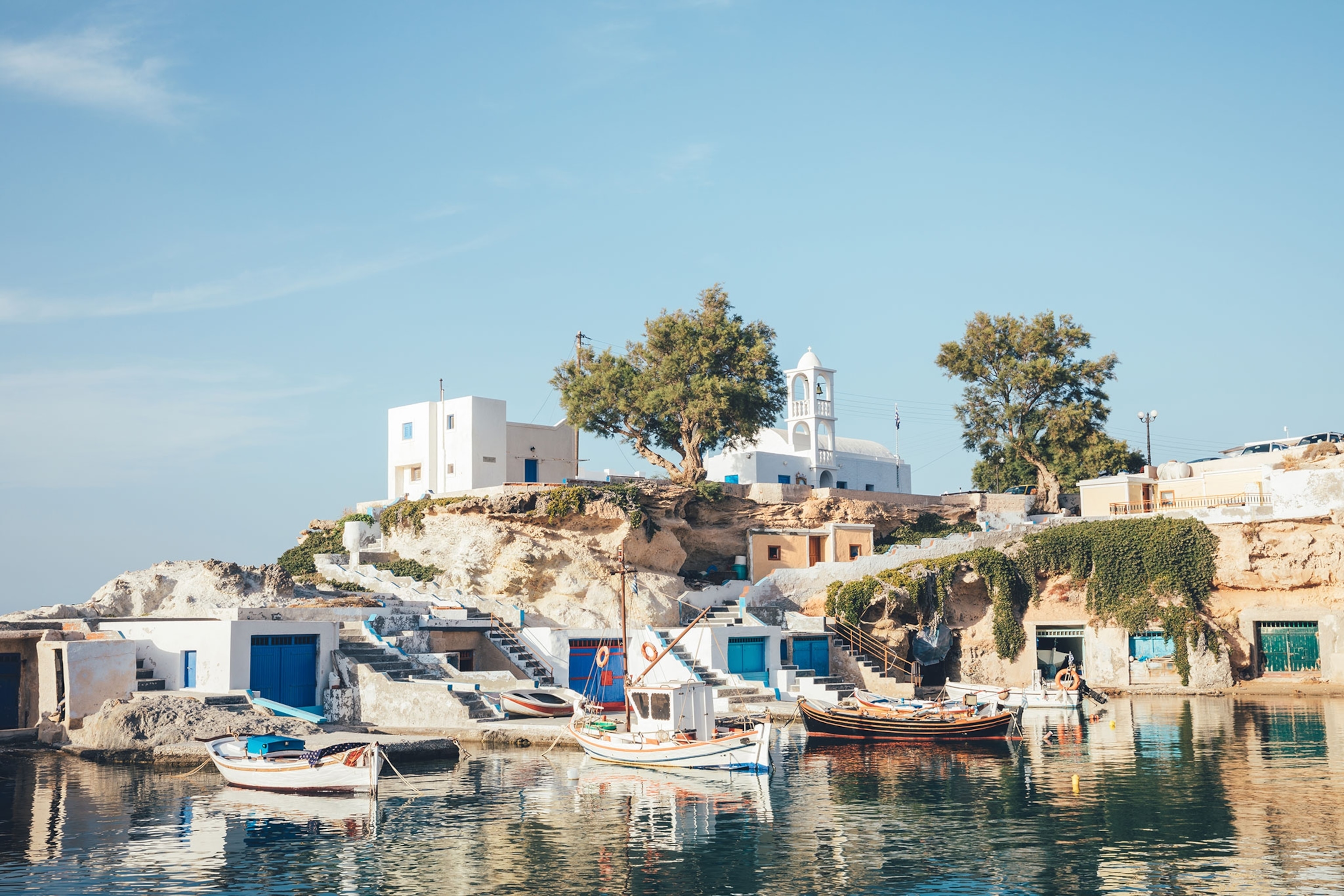 Small village on the edge of blue water surrounded by boats.