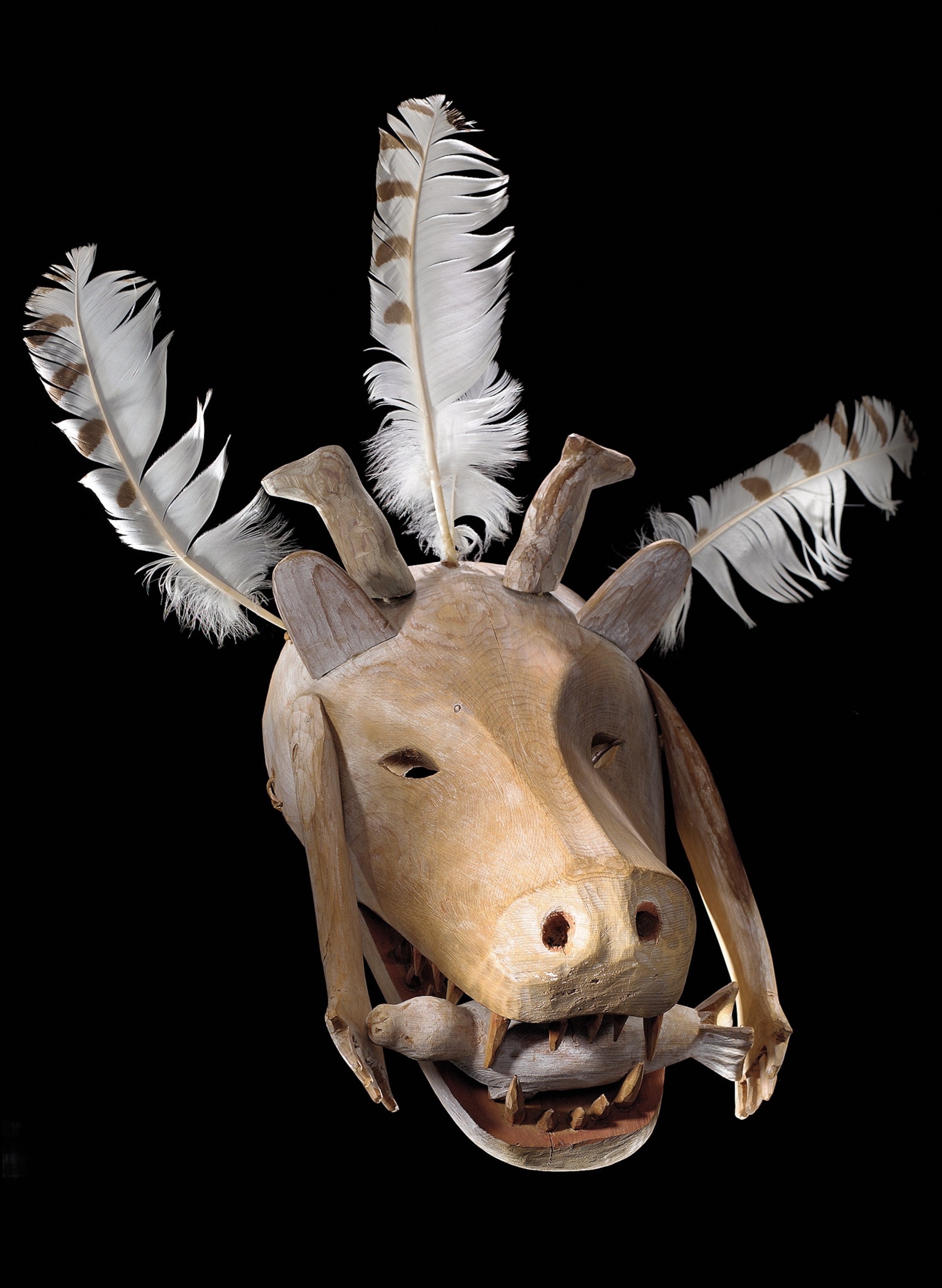 A wooden Yup'ik mask from the 19th century depicts an animal with a seal caught in its jaws. Masks served sacred purposes and were used to petition the gods.