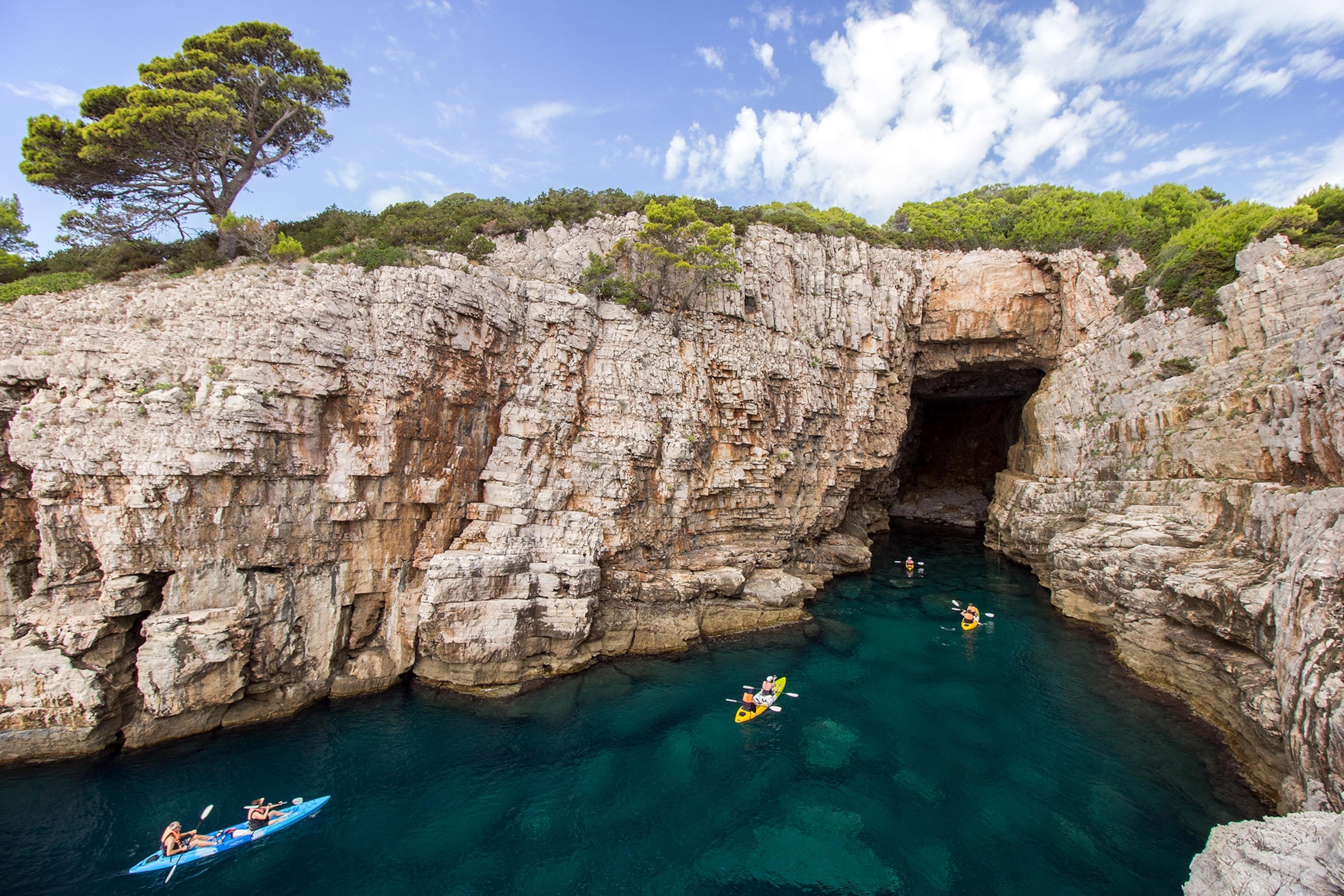 a group of kayakers at a sea cave at the Lokrum Island in Croatia.