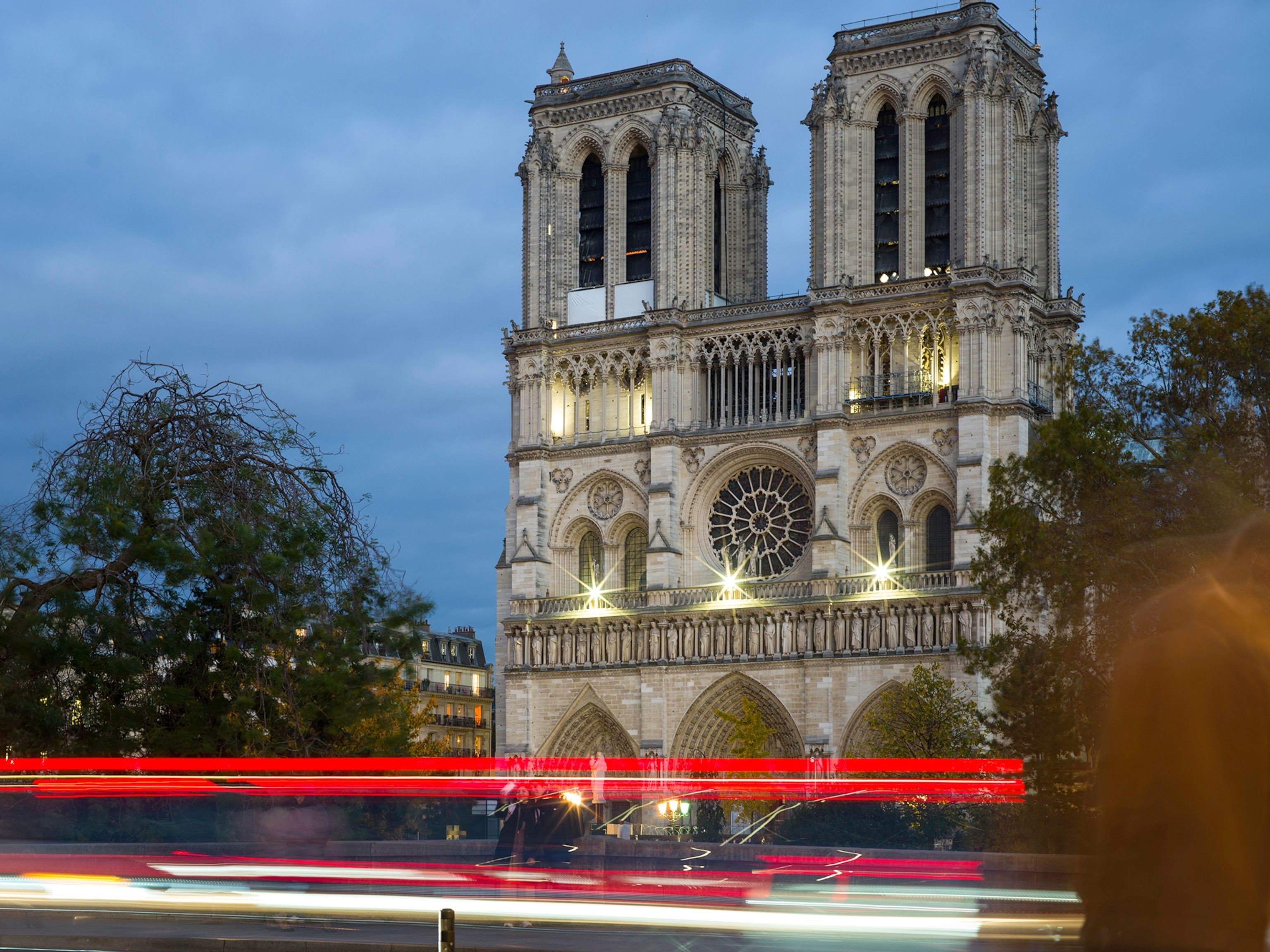 Car lights make streaks of red light as they pass by Notre-Dame Cathedral in Paris.
