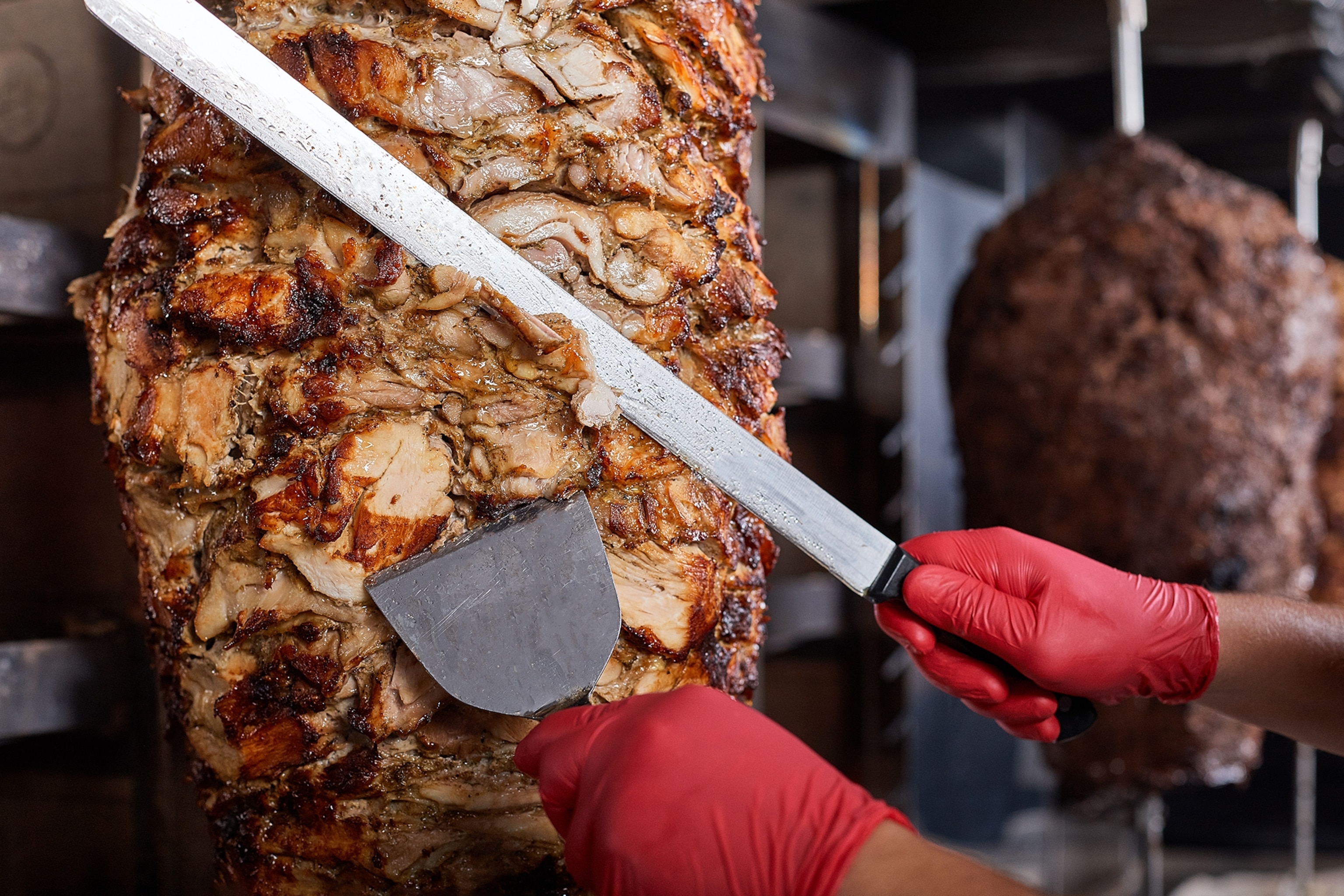 Chef cutting kebab meat from the spit.
