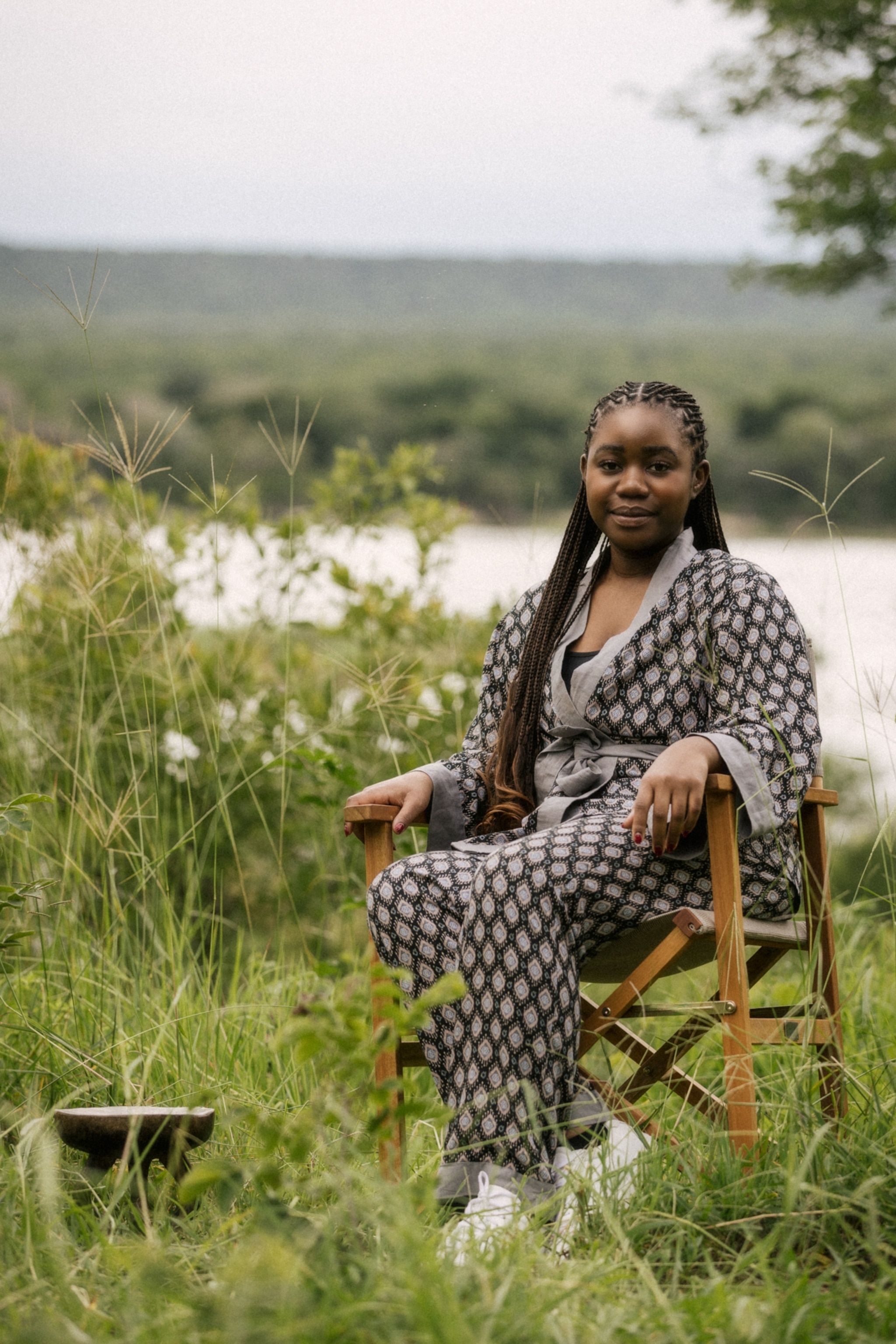 A woman sits in a chair with long braids.