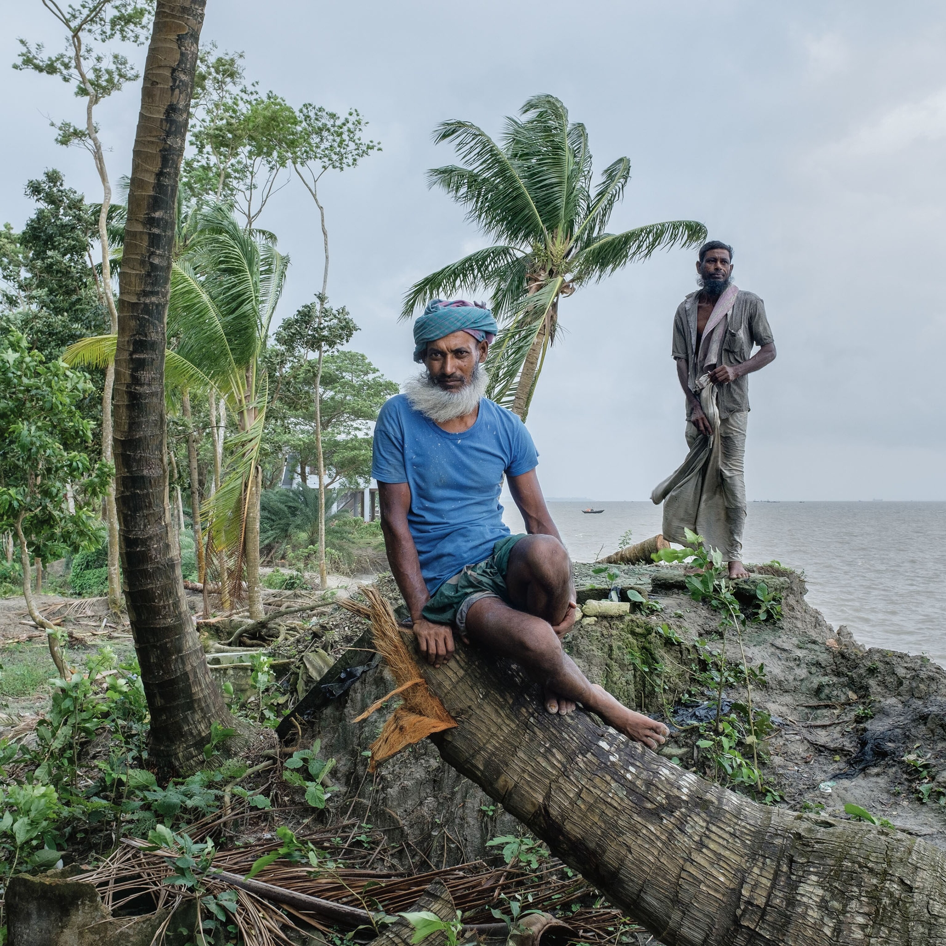 two people standing for a portrait by a coast of water