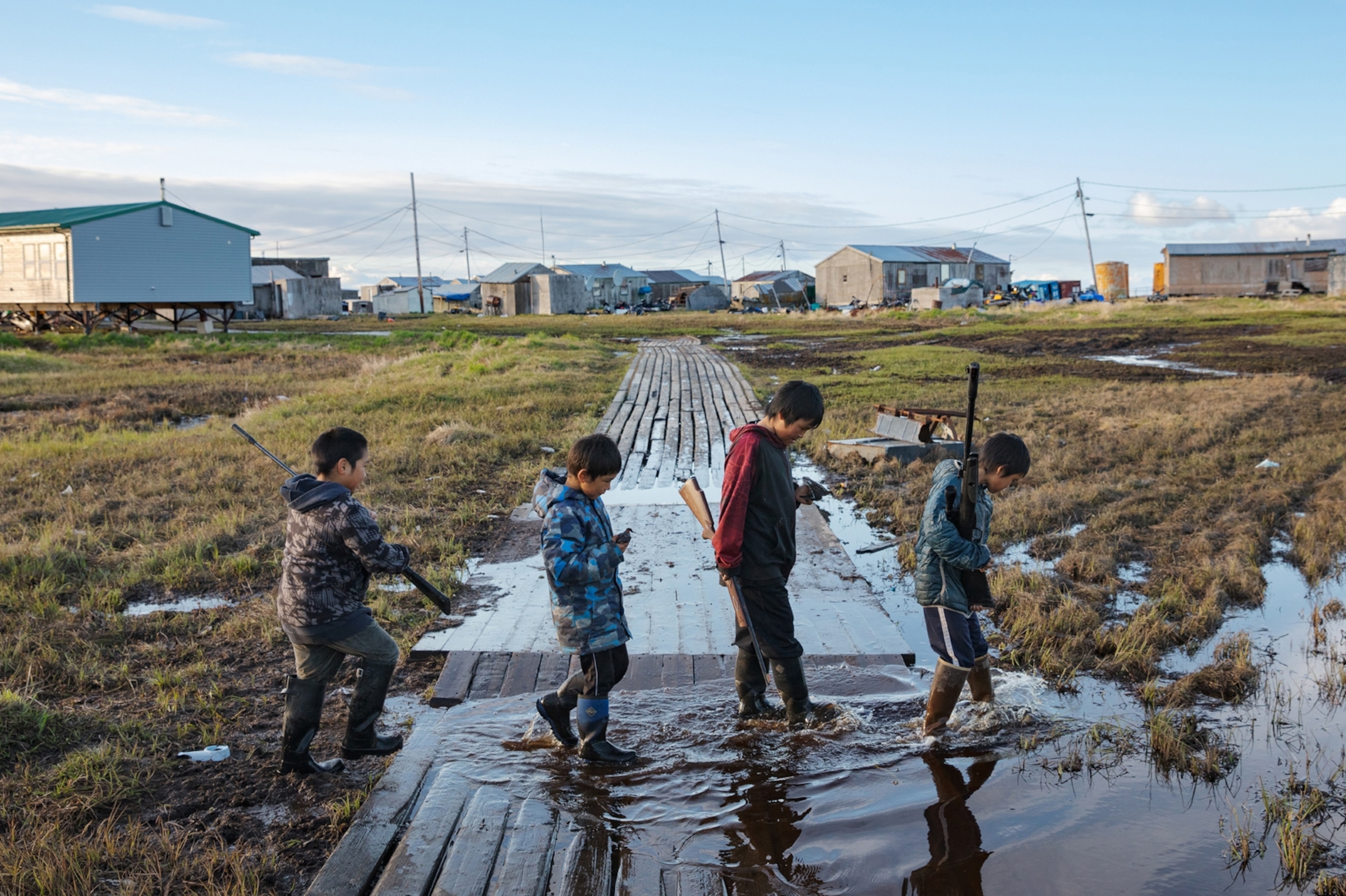 four boys with BB guns crossing flooded walkway.