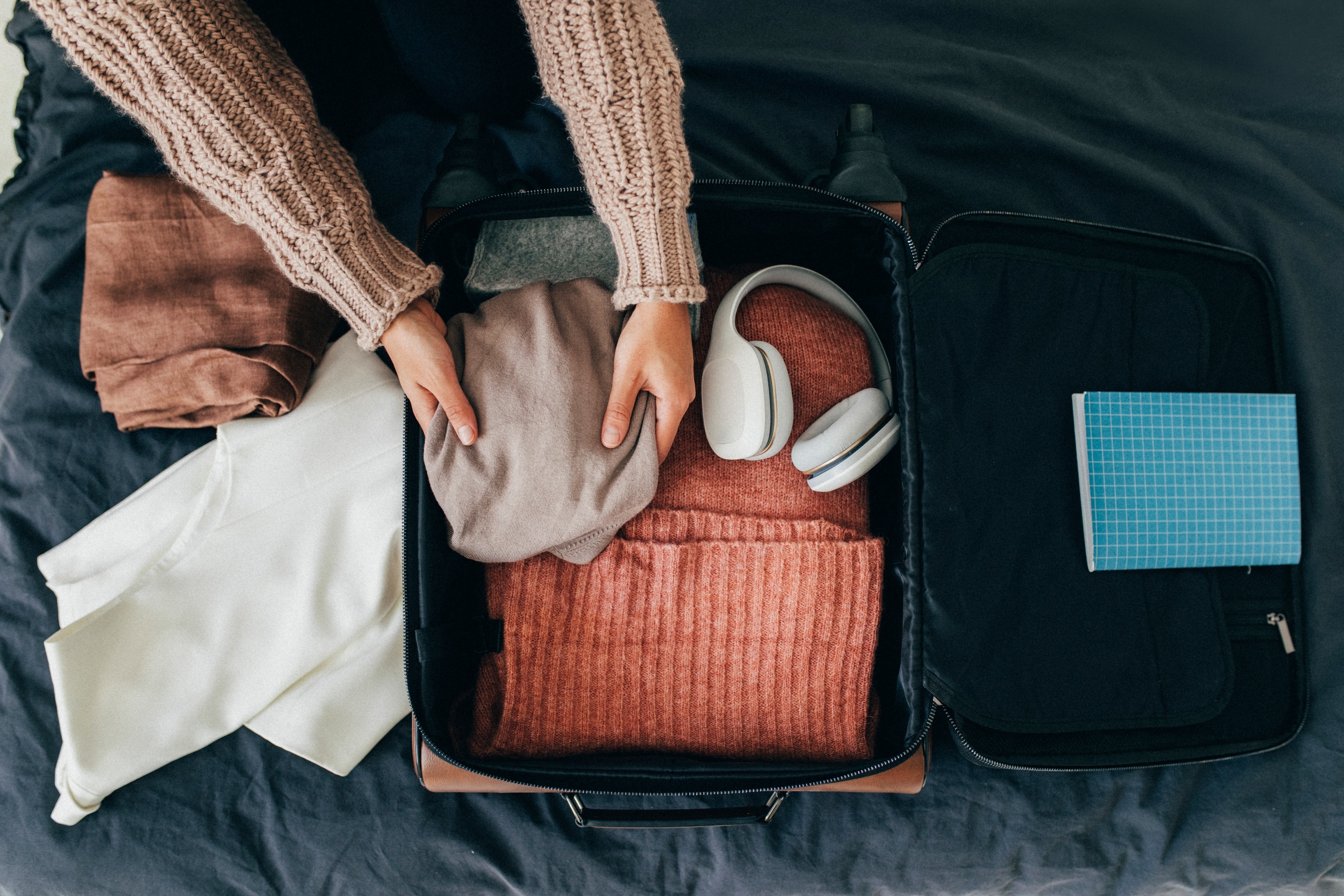 Happy traveller: a woman packing her clothes into a suitcase, getting ready for a trip.