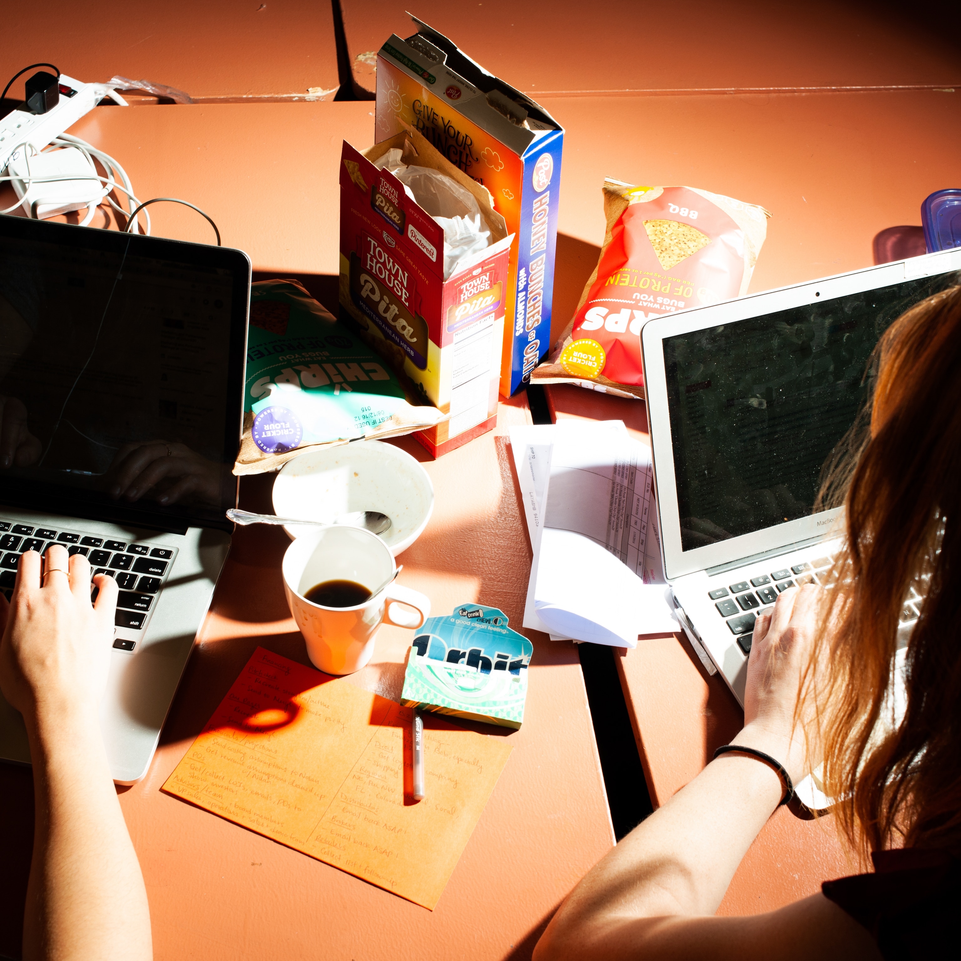 two people eat over their computers at their desks