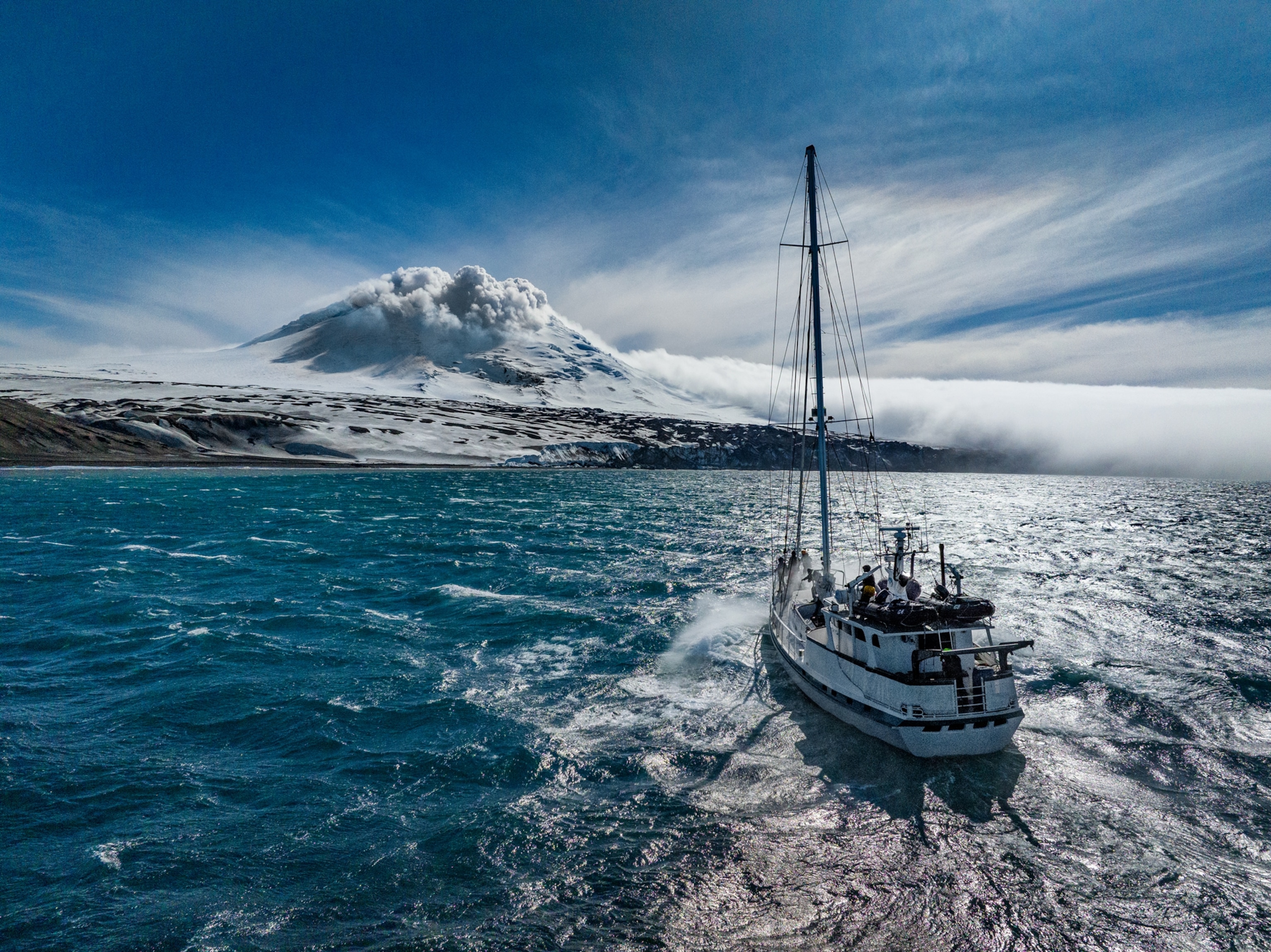 Sailboat approaching the island covered with snow and ice.