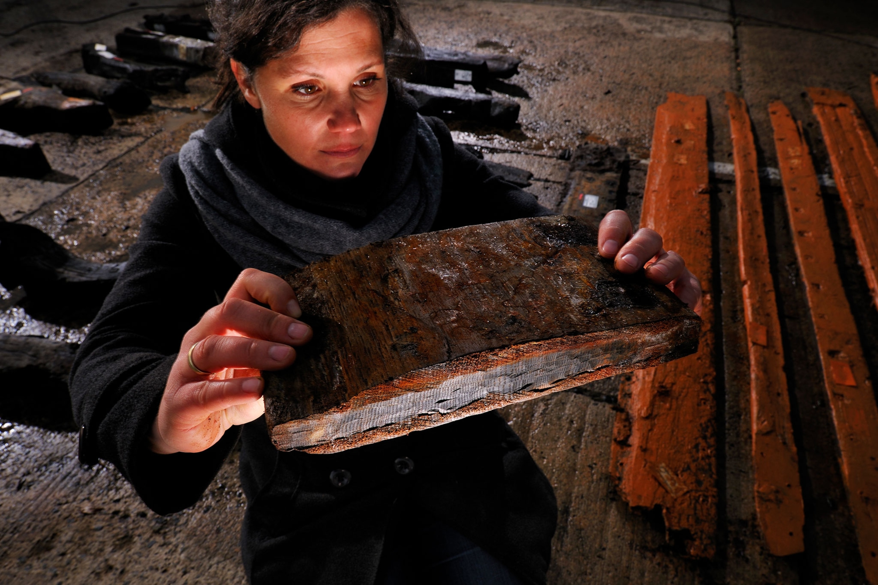 A photograph of a woman analyzing the timber from a ship
