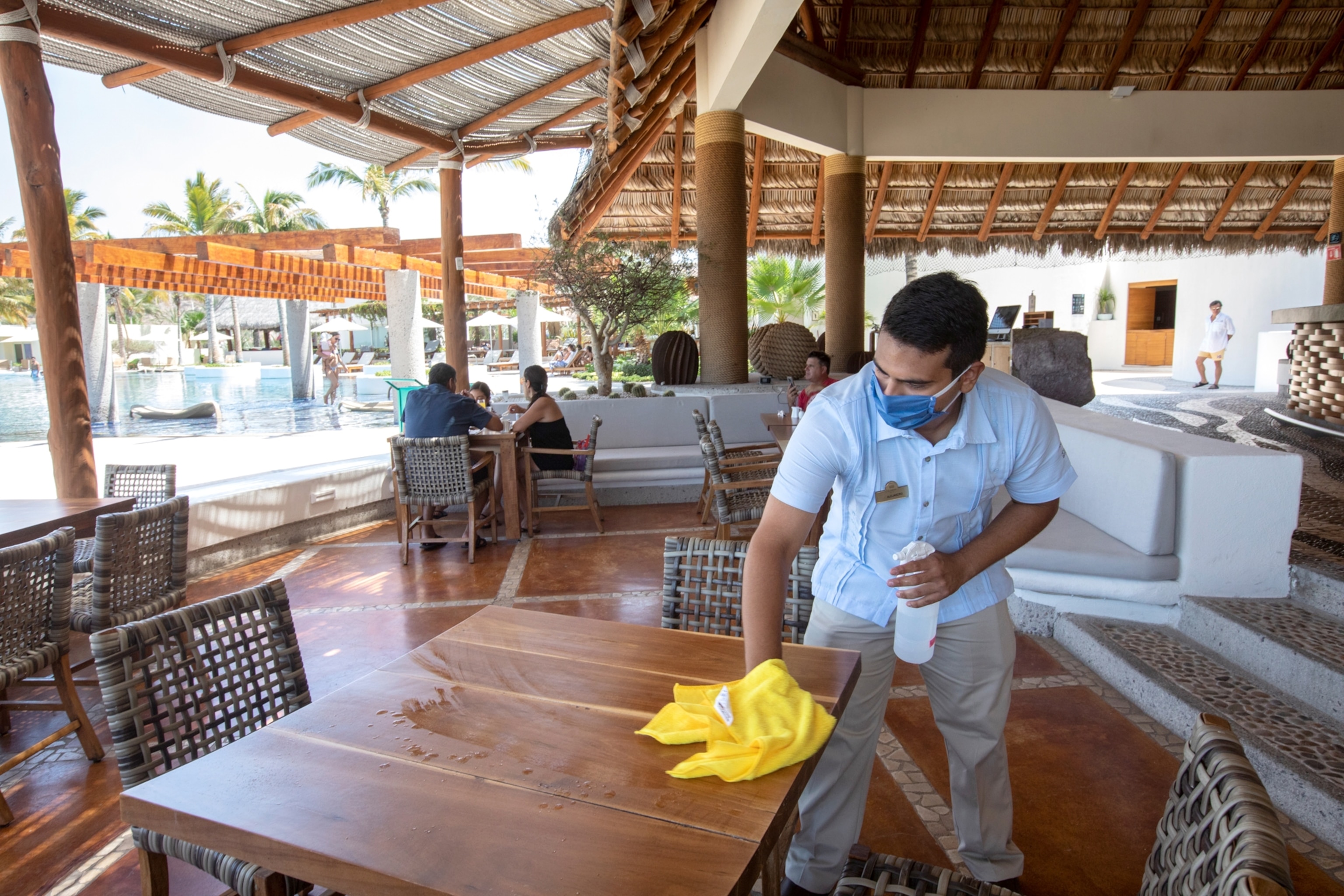A waiter at the Blue Cortés beach club sanitizes a table in La Paz, Mexico