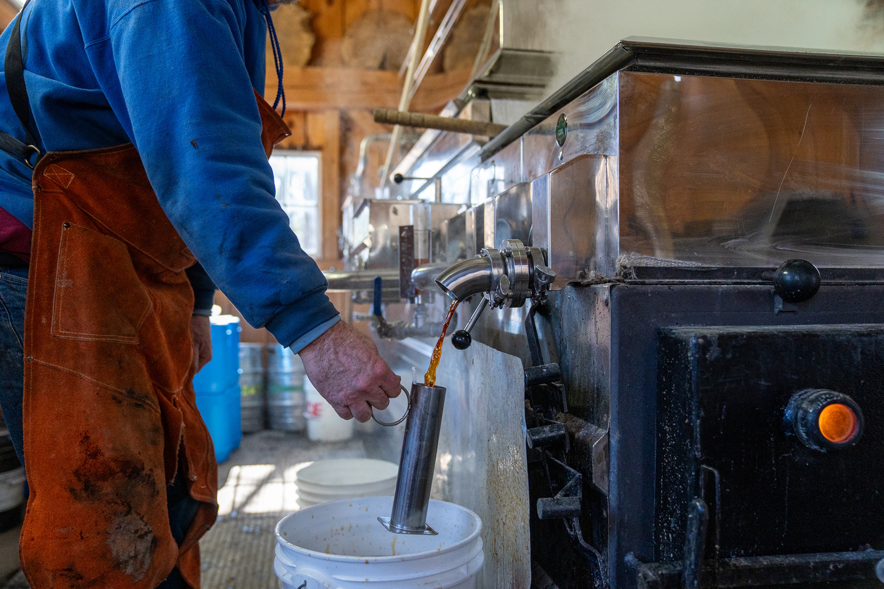 Pat LeClaire pours freshly made maple syrup from an evaporator into a beaker to measure its density March 8, 2024 in Charlotte, Vermont. Fresh maple syrup comes out of the evaporator at 218F degrees.