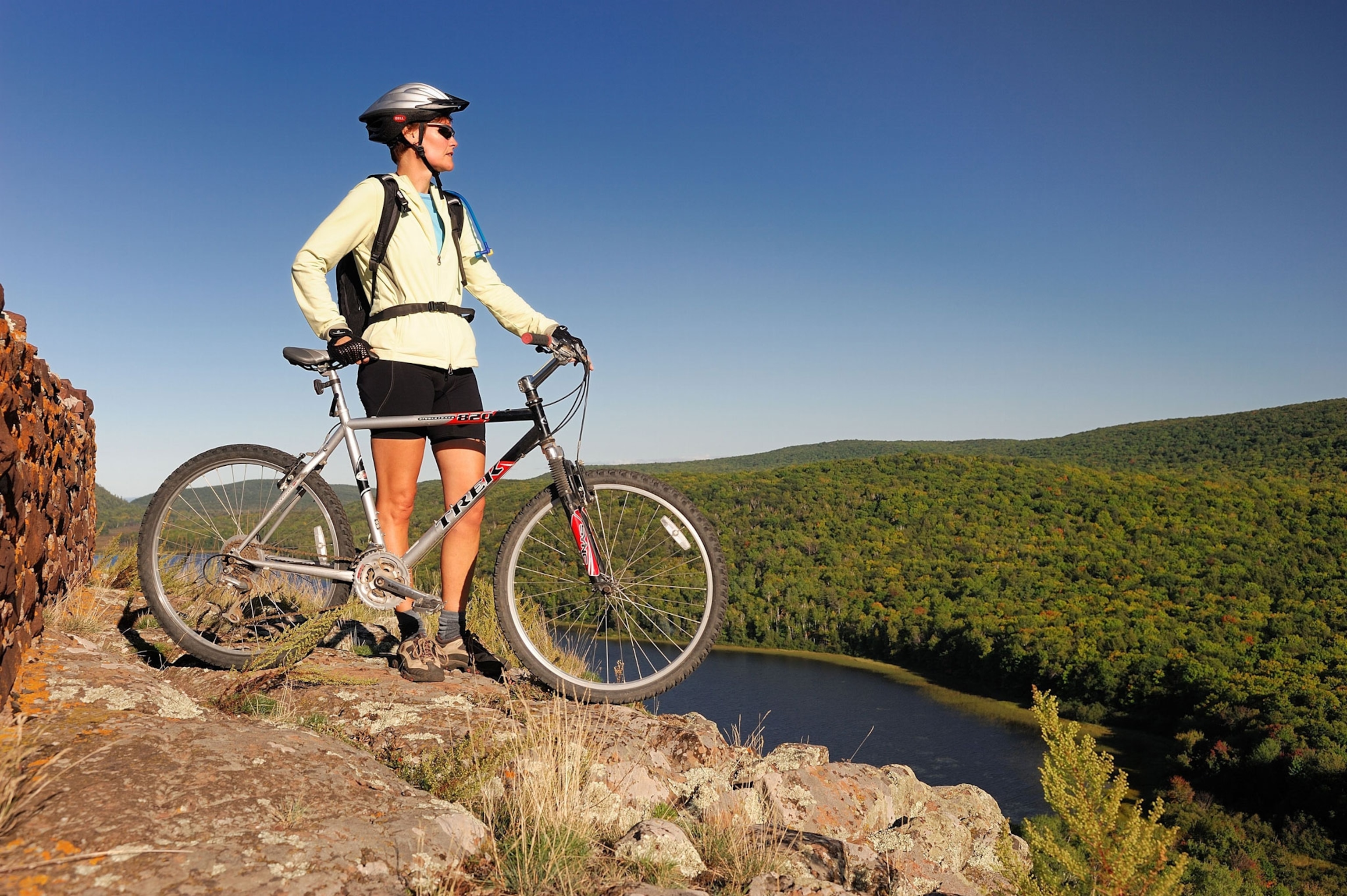a woman resting with her bike at the edge of a cliff