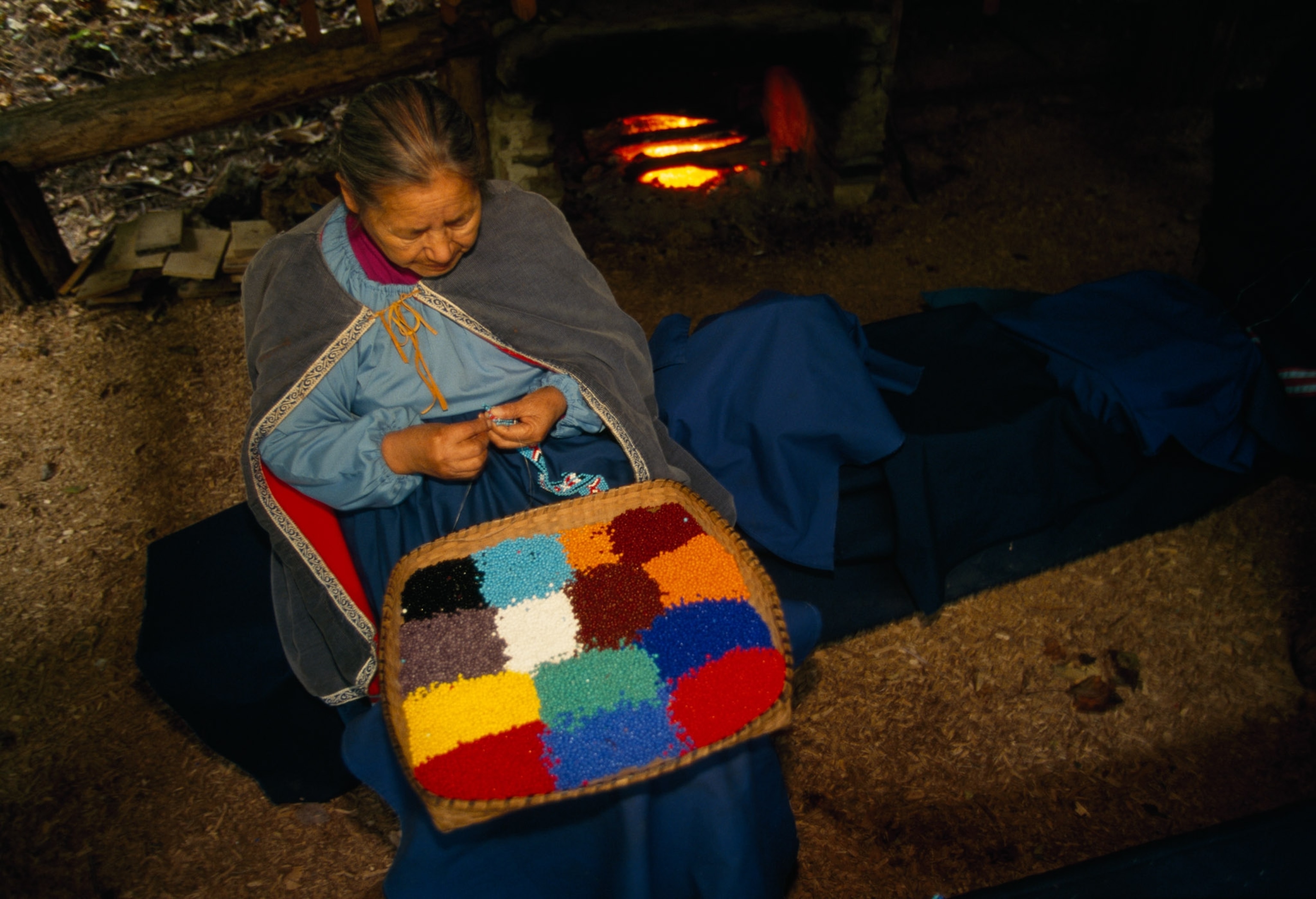 Woman sits sewing.