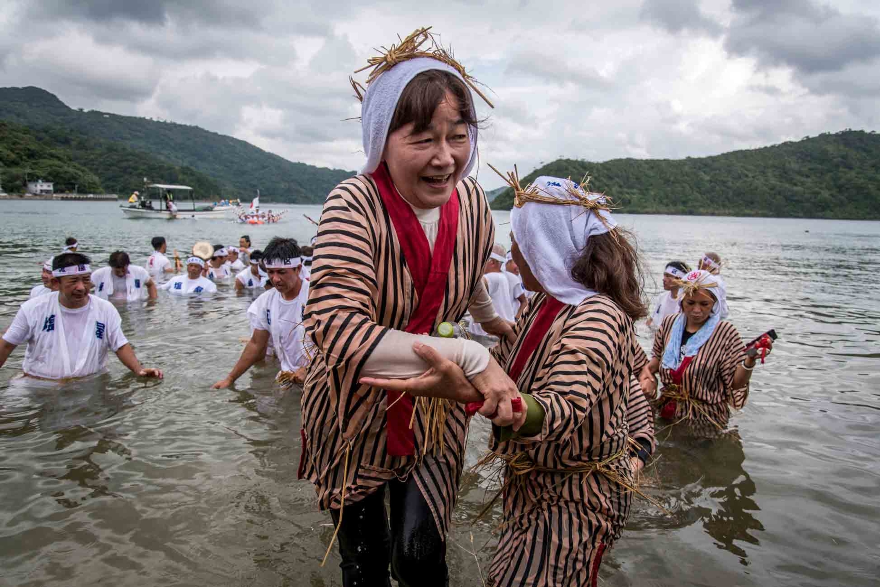 an elderly woman emerging from the Shioya Bay during the Ungami Festival, Okinawa
