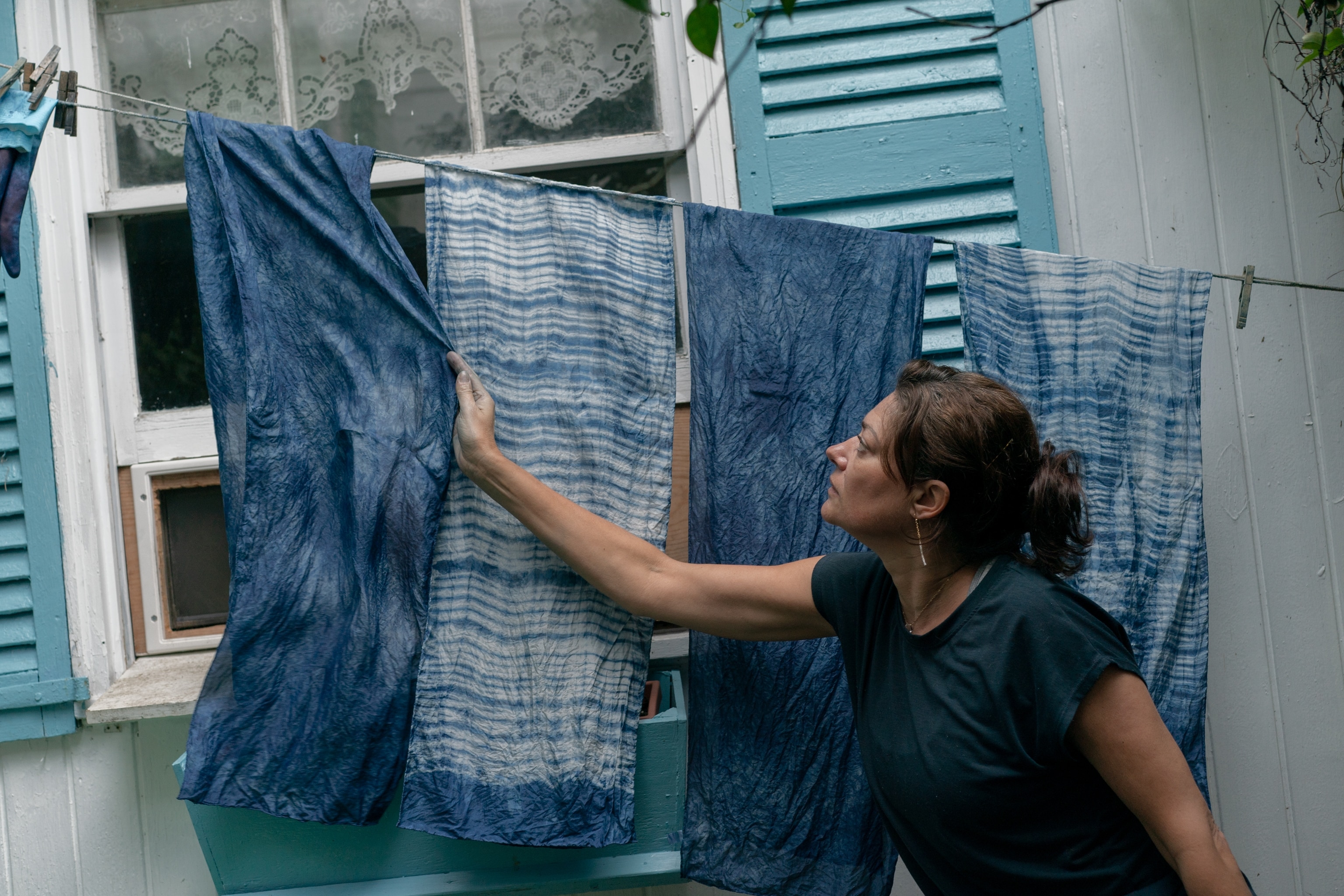Caroline Harper straightens out some of her scarves dyed with indigo at her home in Charleston, South Carolina