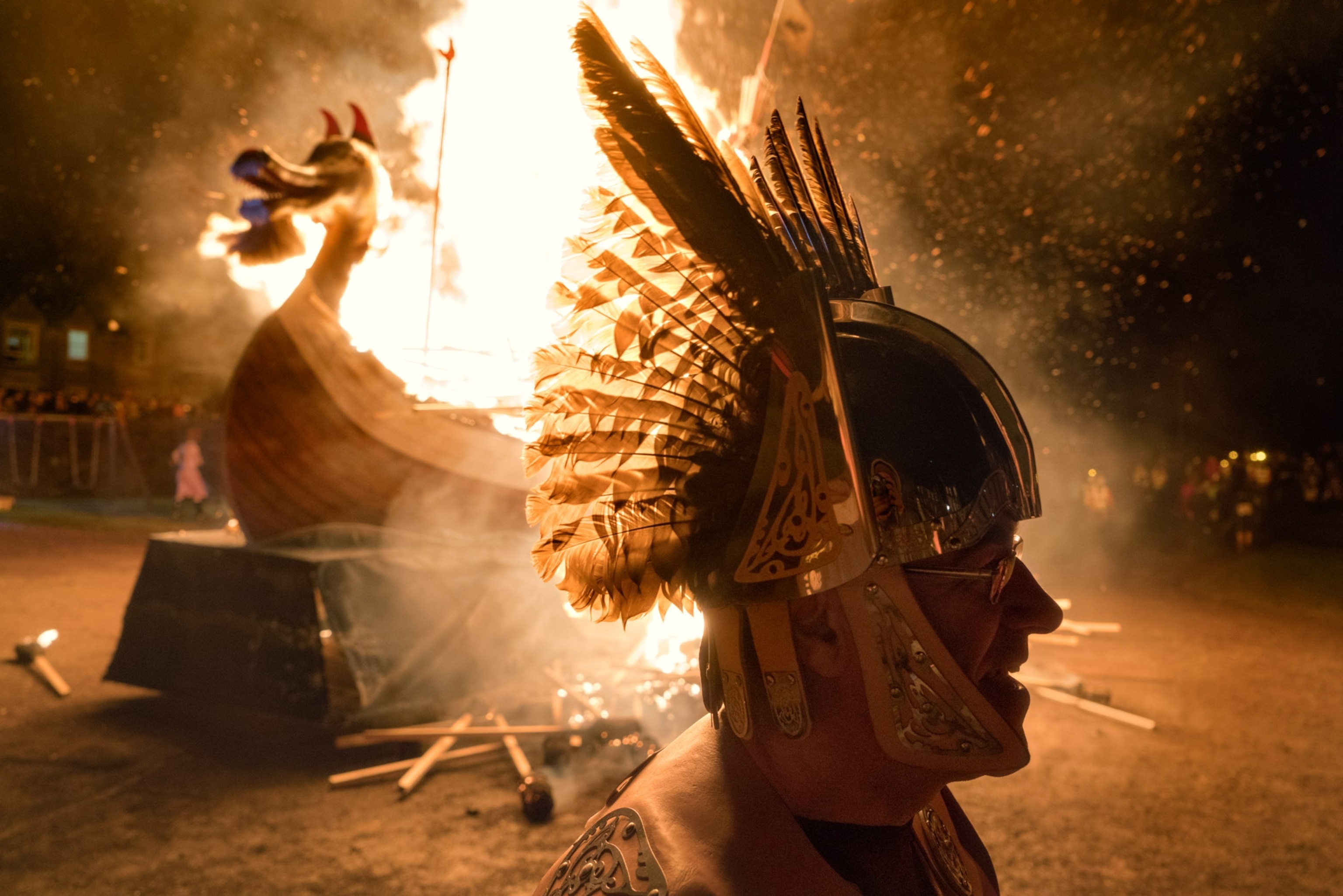 A fire rages behind a man in a winged helmet.