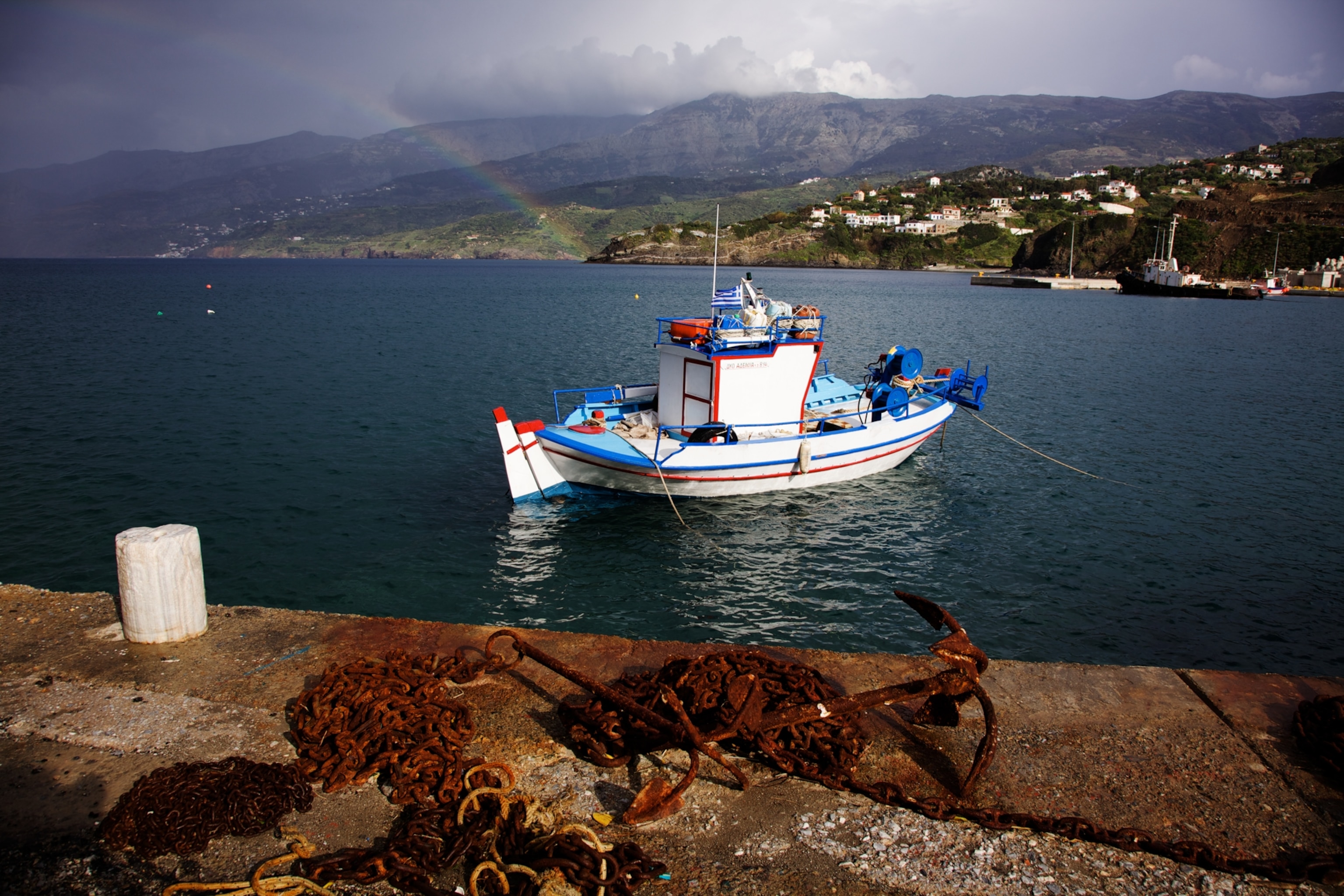 A rainbow and a fishing boat along the coast of Ikaria.