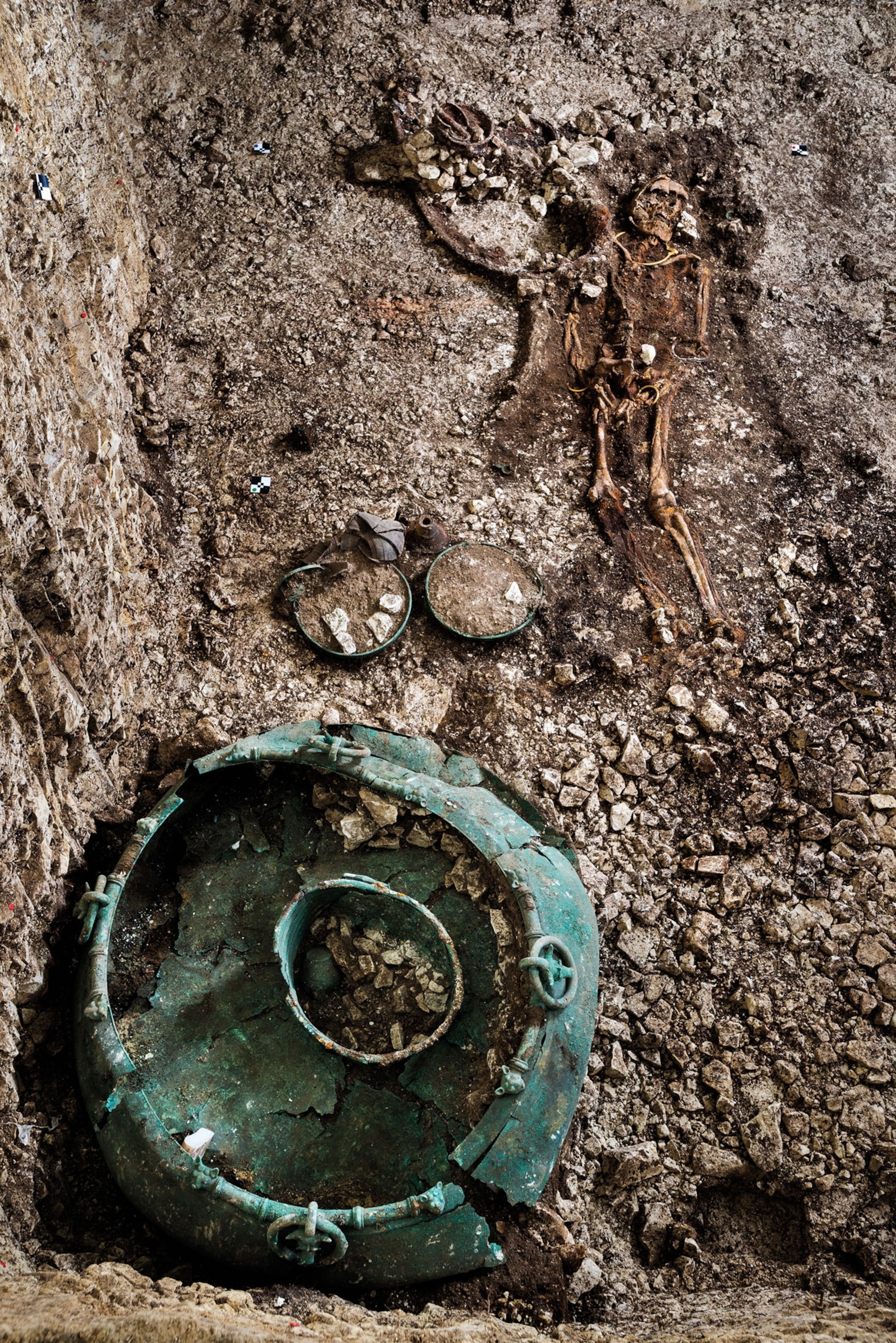 A skeleton half buried in the ground with a large cauldron at their feet