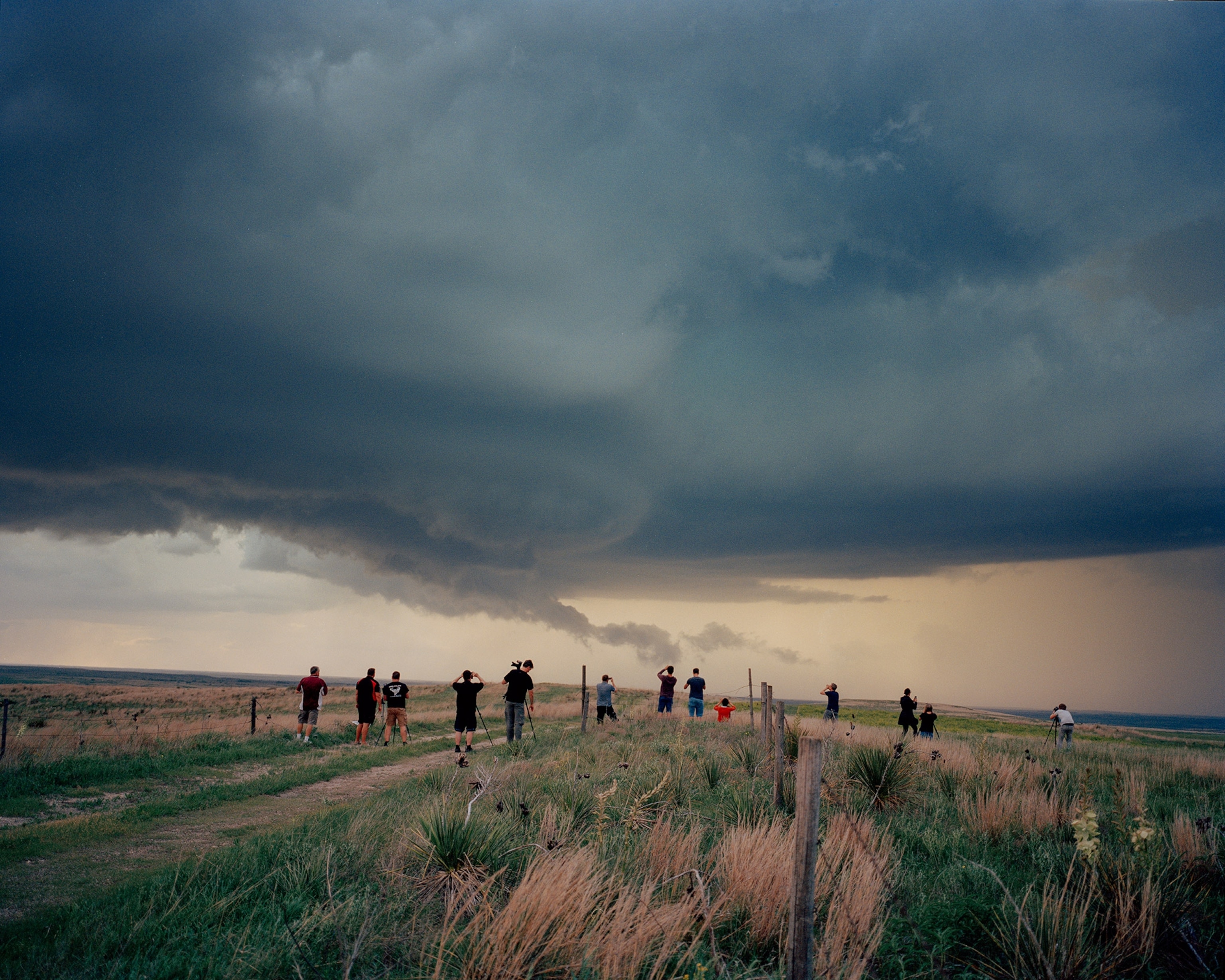 Storm chasers stand in a row to photograph the storm in the sky