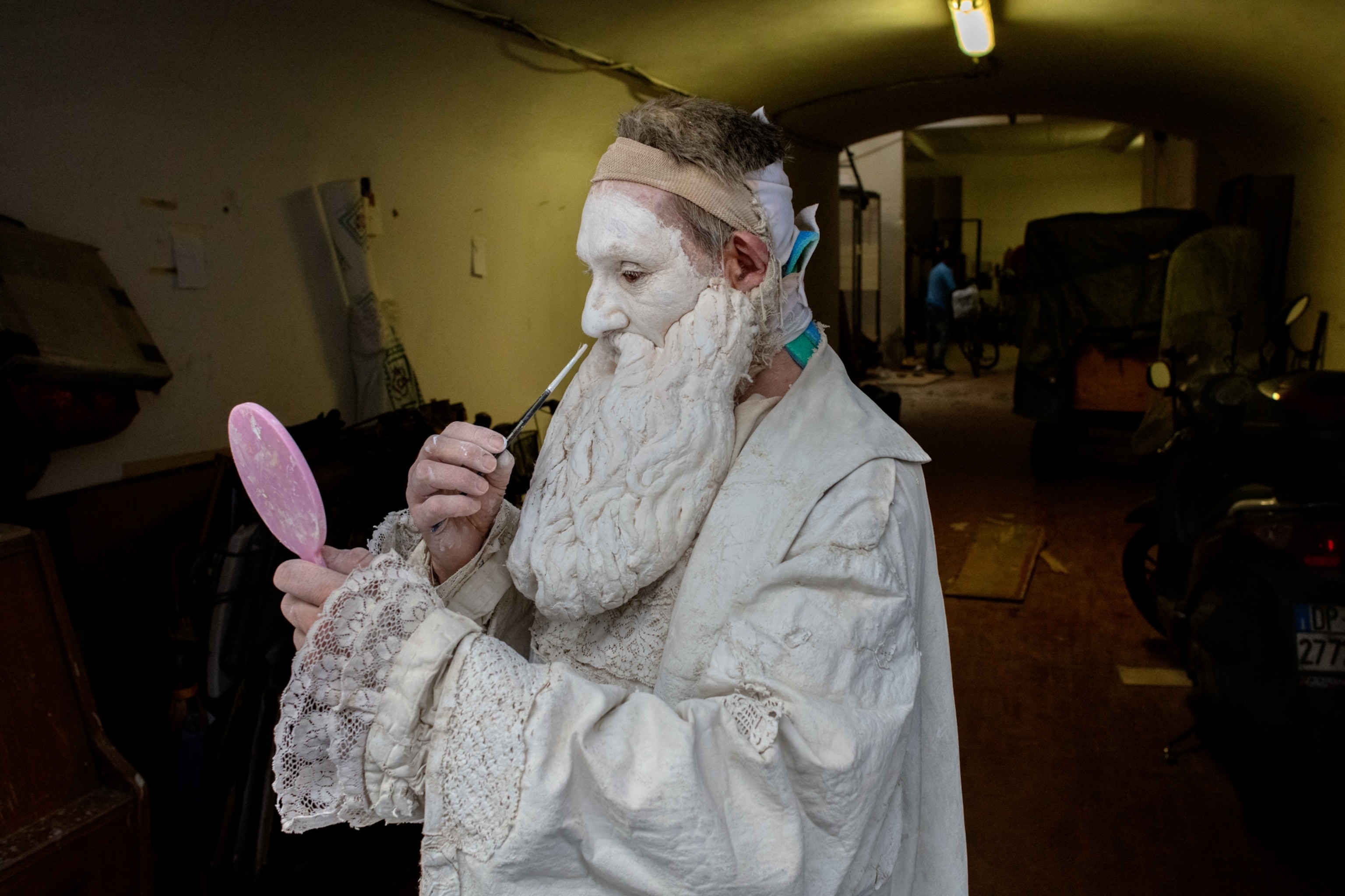 an medieval impersonator touching up his all white painted beard