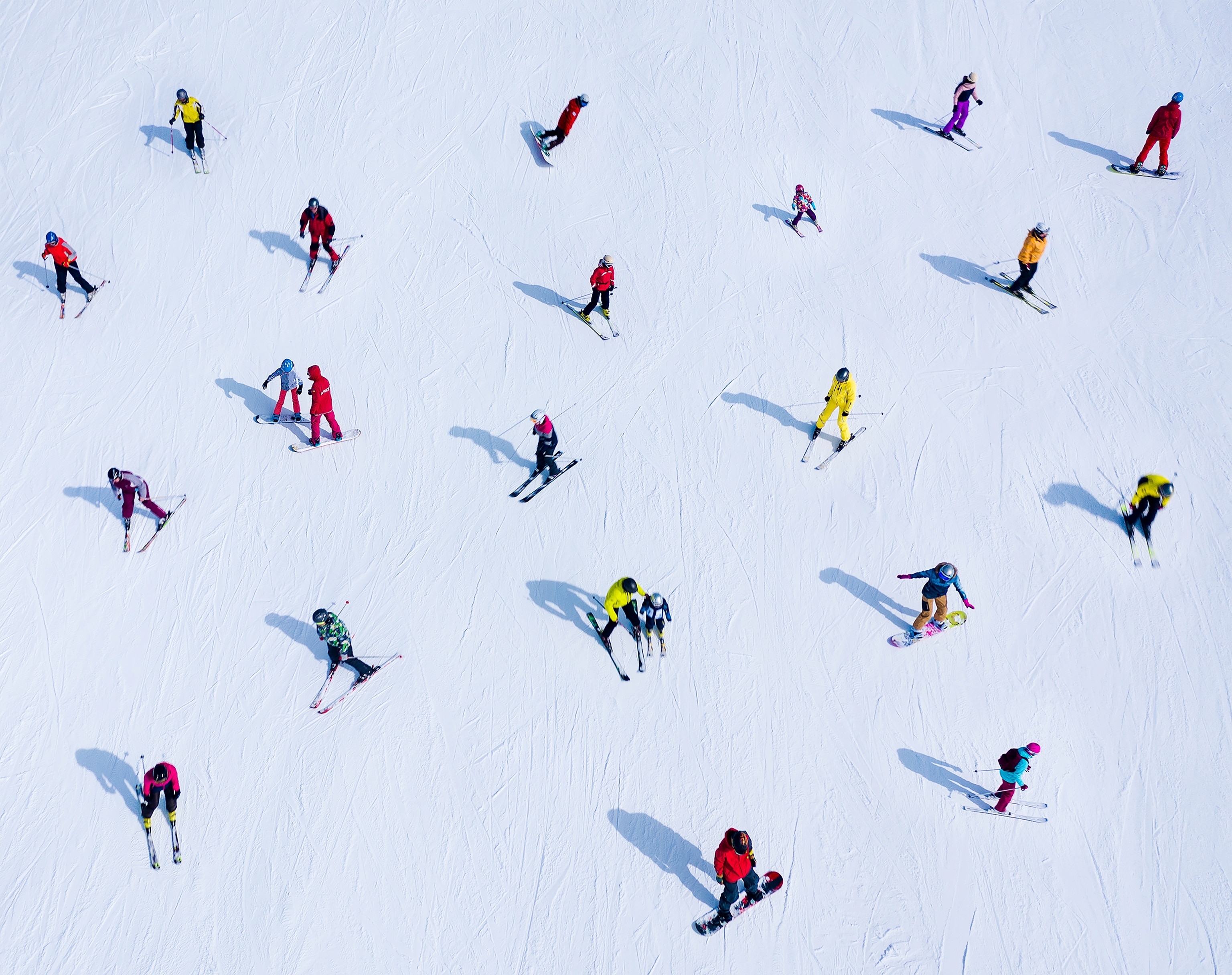 Many skiers and snowboarders are located on the side of the mountain