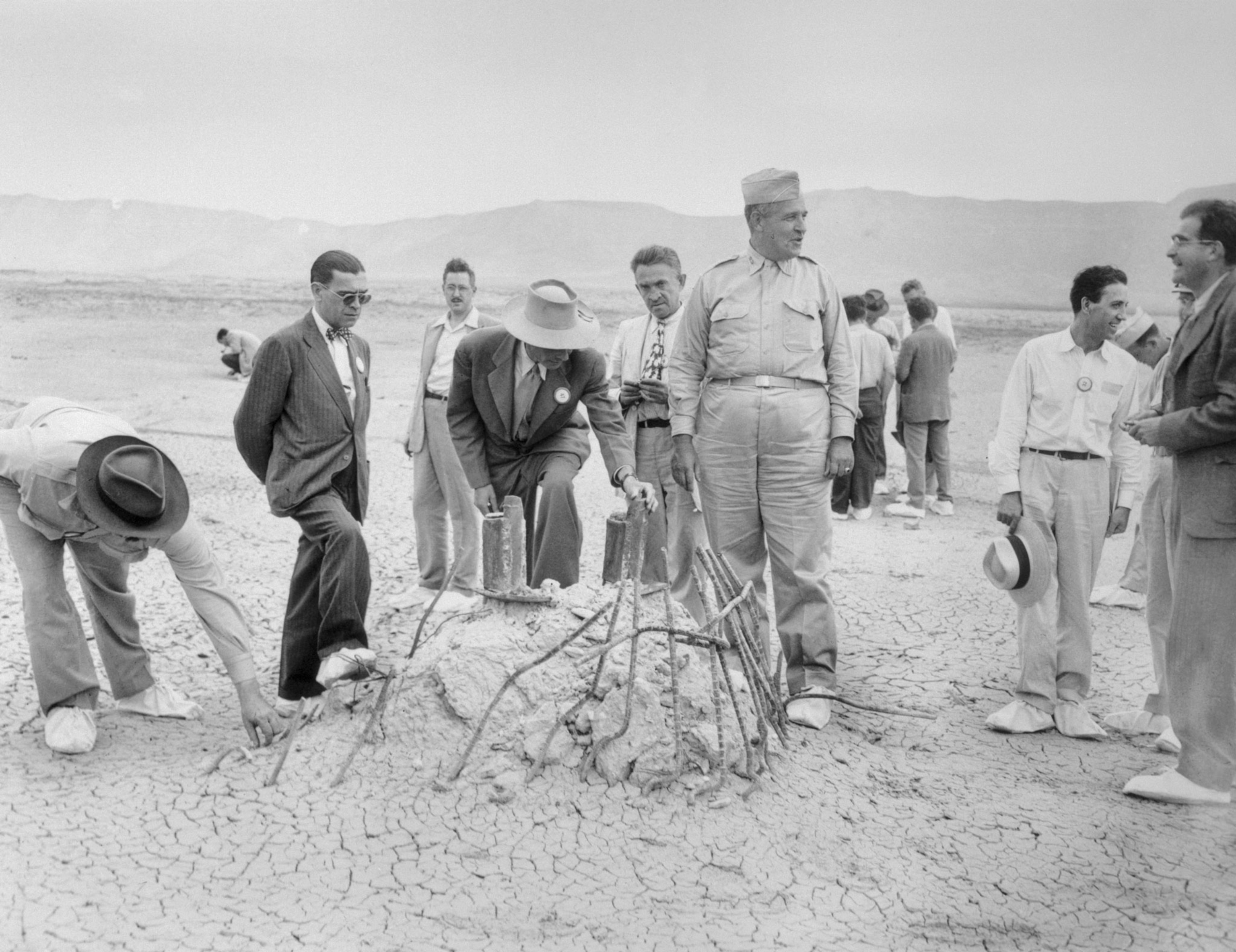 men gather around the remains of a steel tower in the desert
