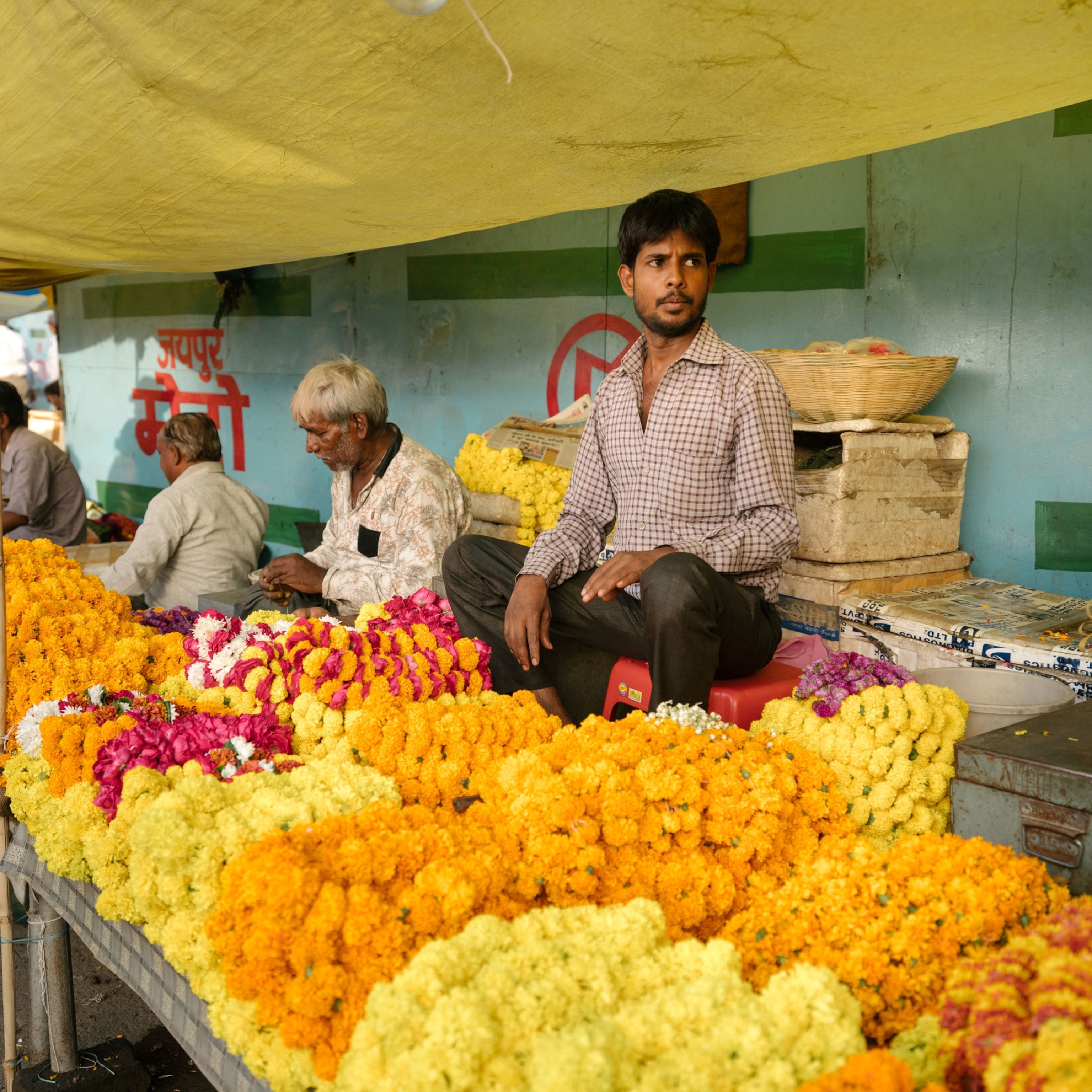 Flower seller's booth filled with yellow, orange, and pink flowers