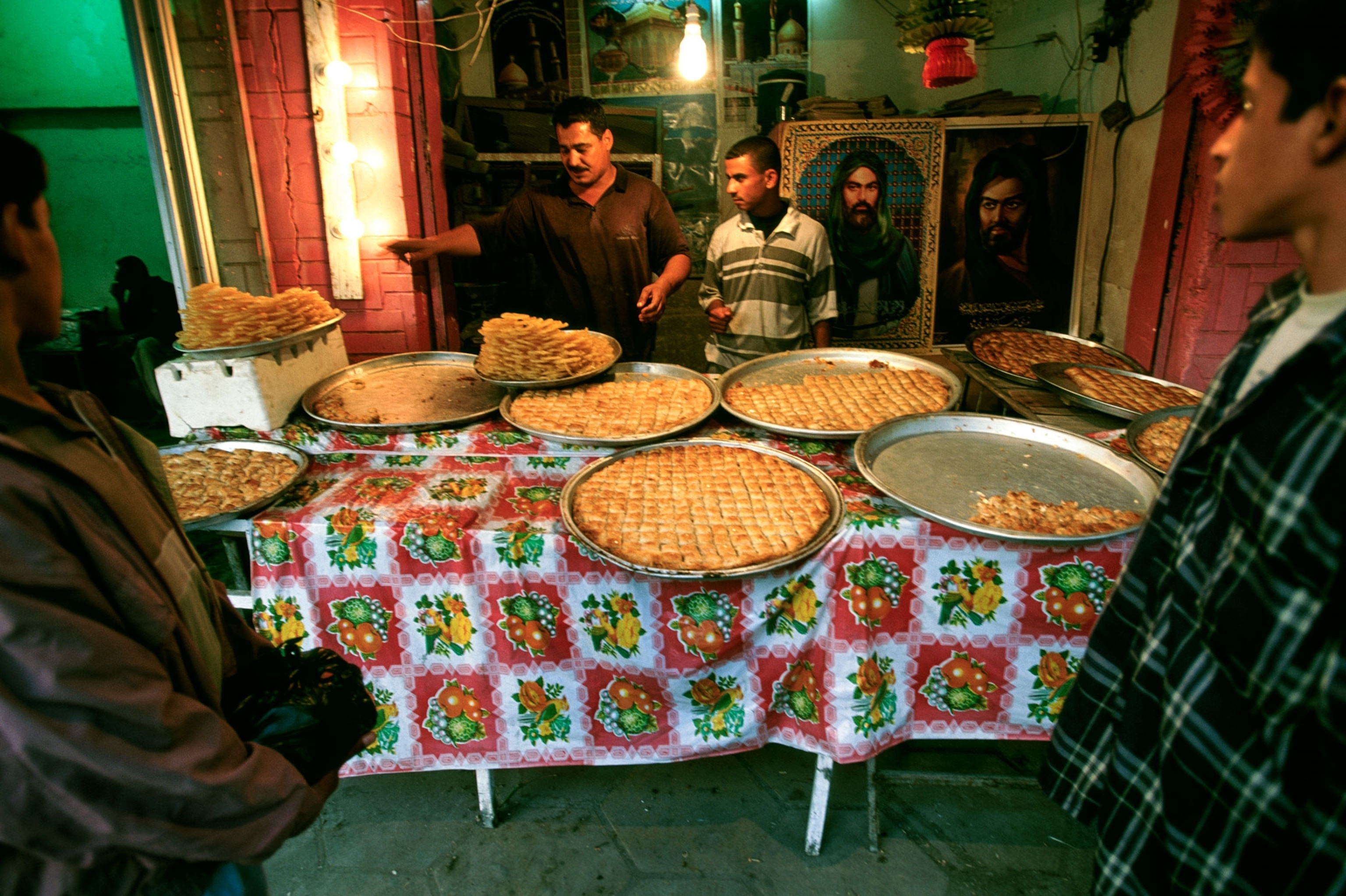 Men sell pastries displayed on a street side table prior to Iftar.