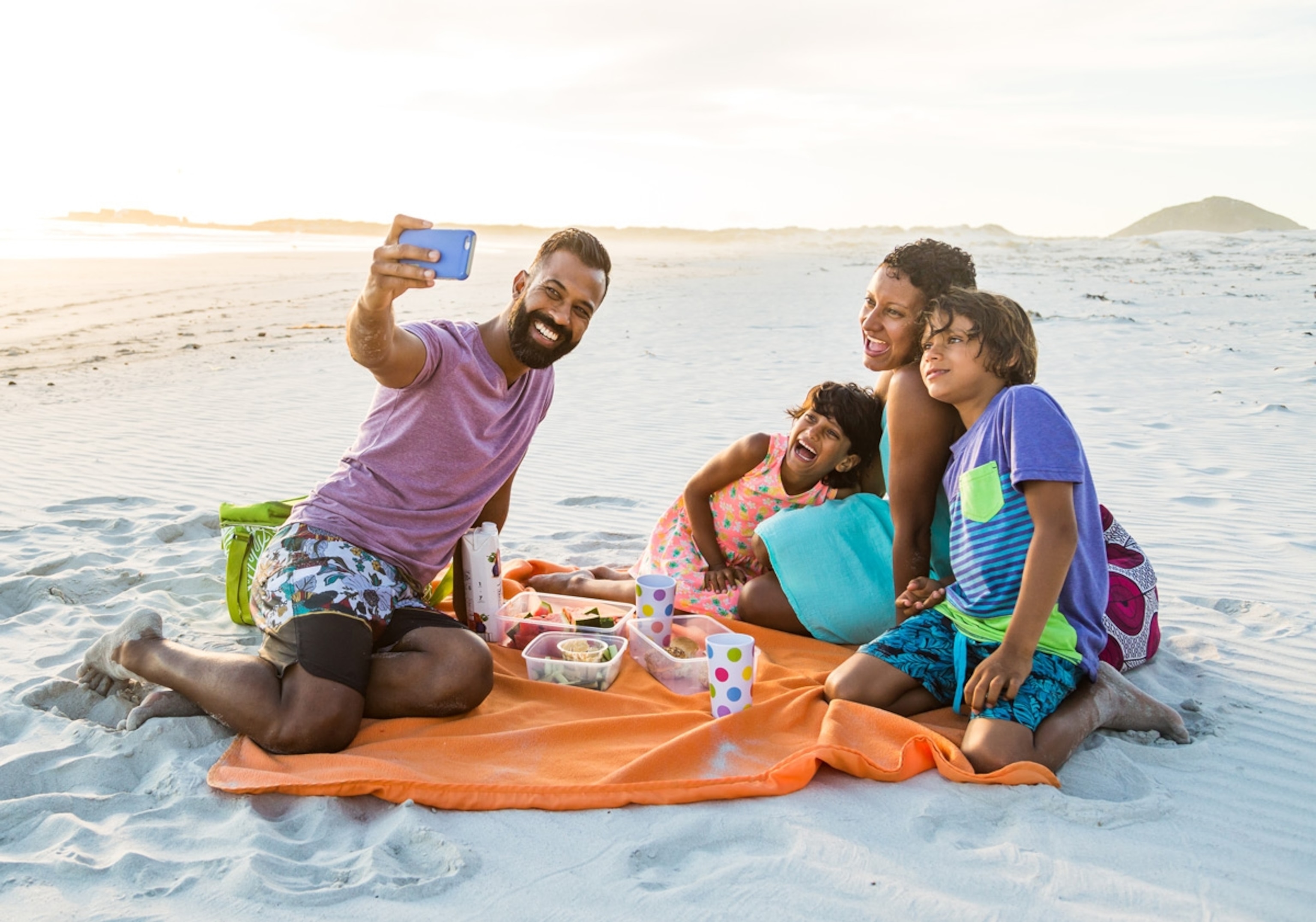 Family taking selfie photo on a beach at sunset. South Africa