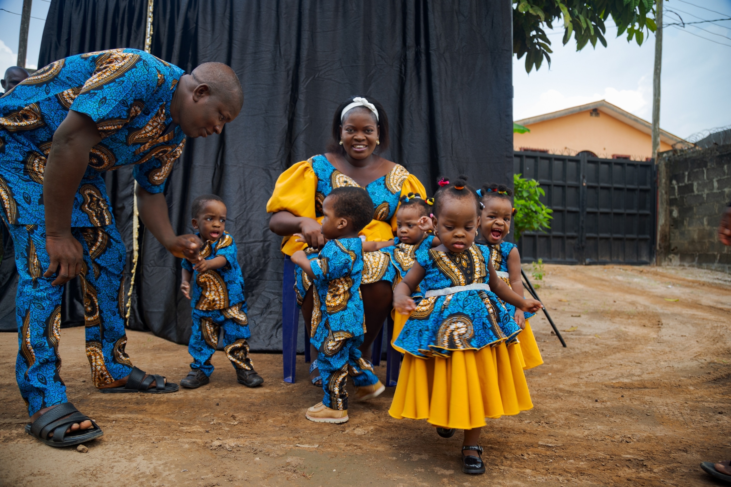 Picture of women smiling in camera surrounded by five children and husband, all dressed in the same color clothes.