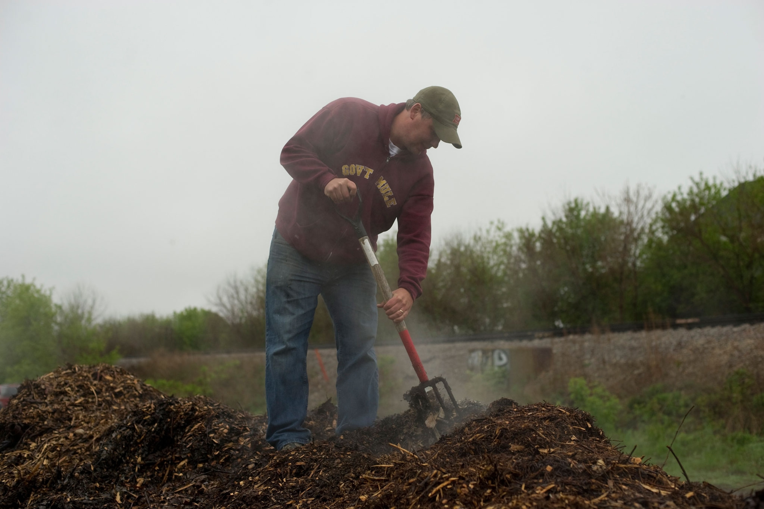 a man shoveling compost
