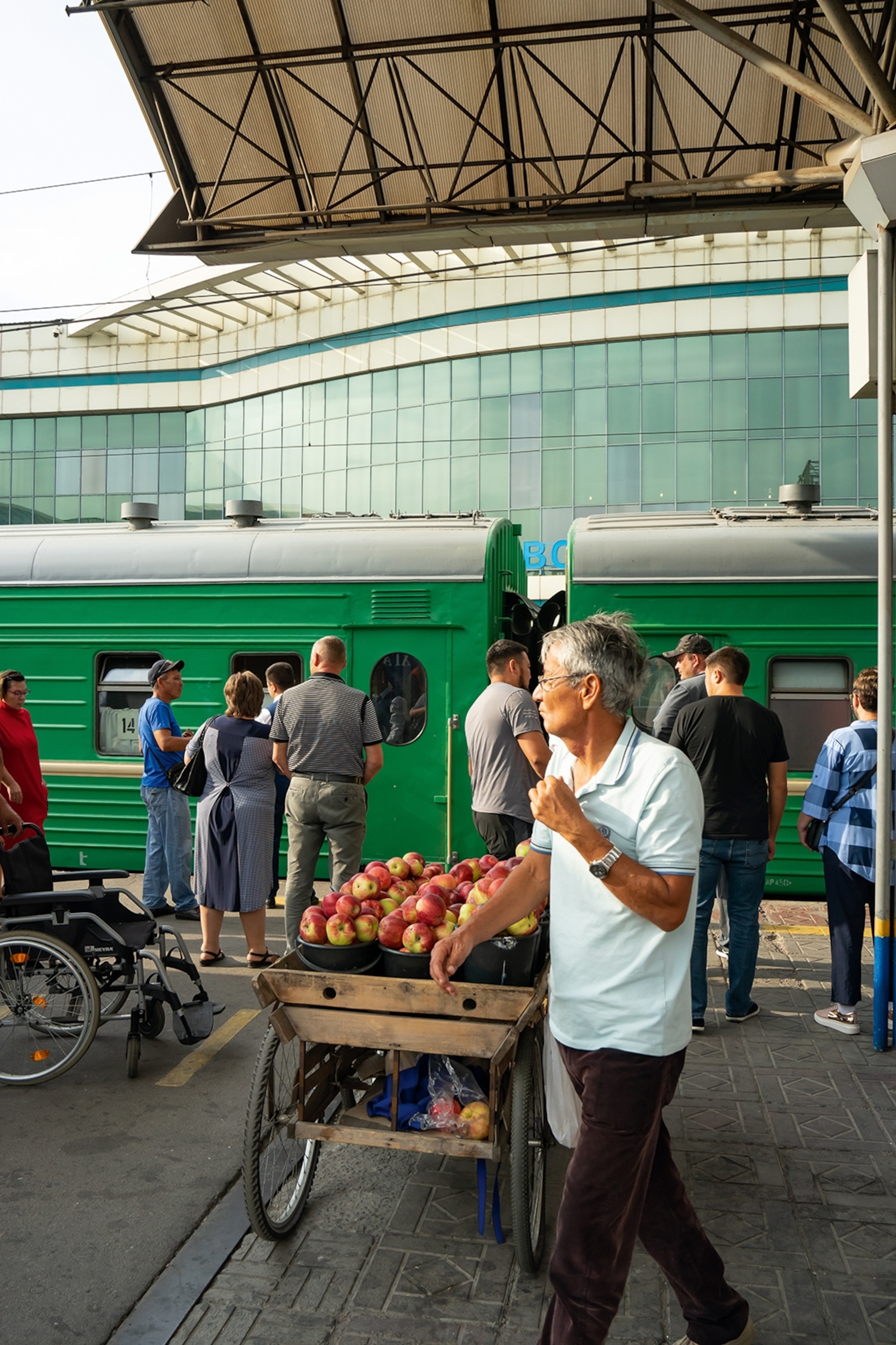 People waiting for a train and a vendor selling apples at a train station in Almaty, Kazakhstan.
