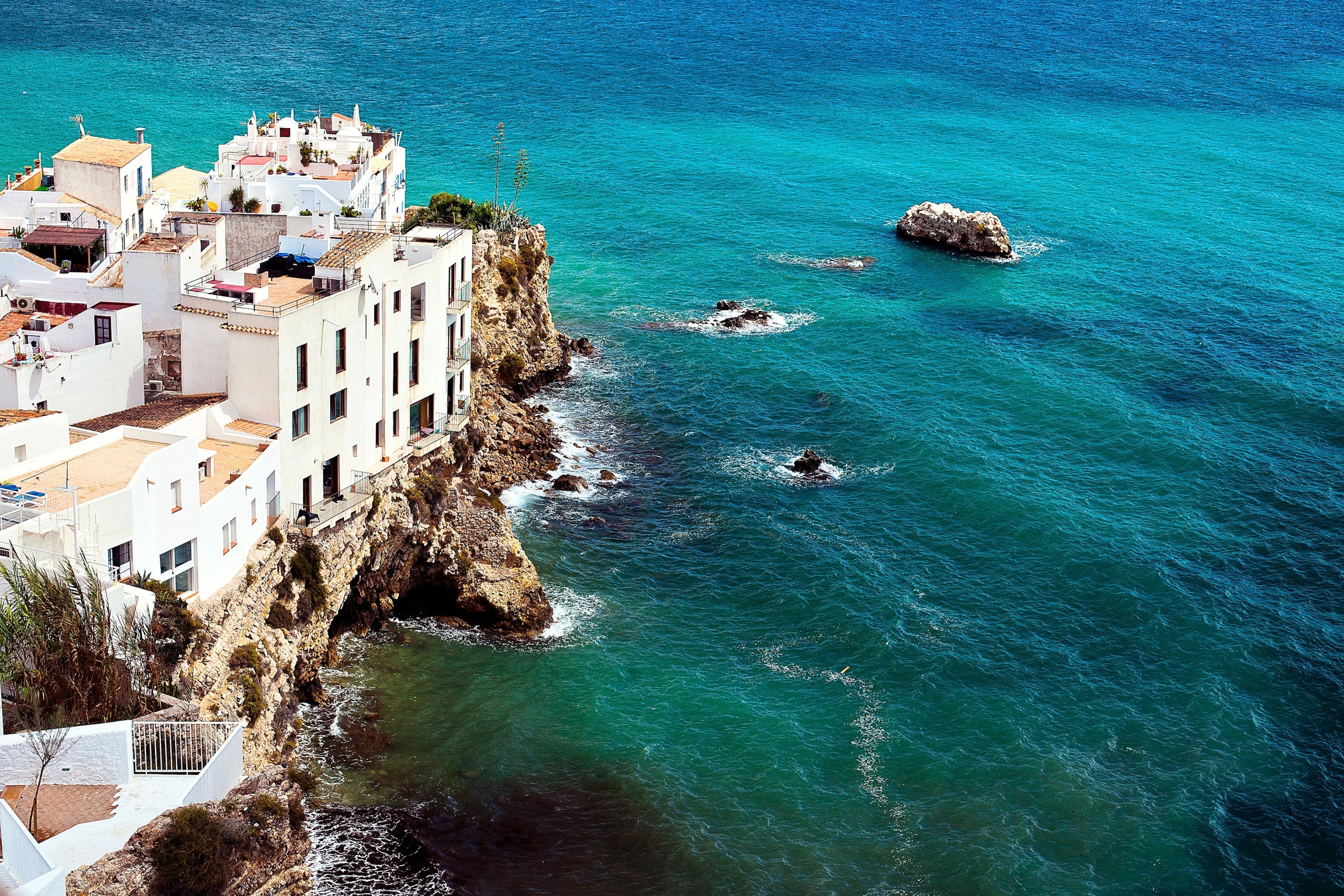 houses perched on rocks above sea in Ibiza, Spain