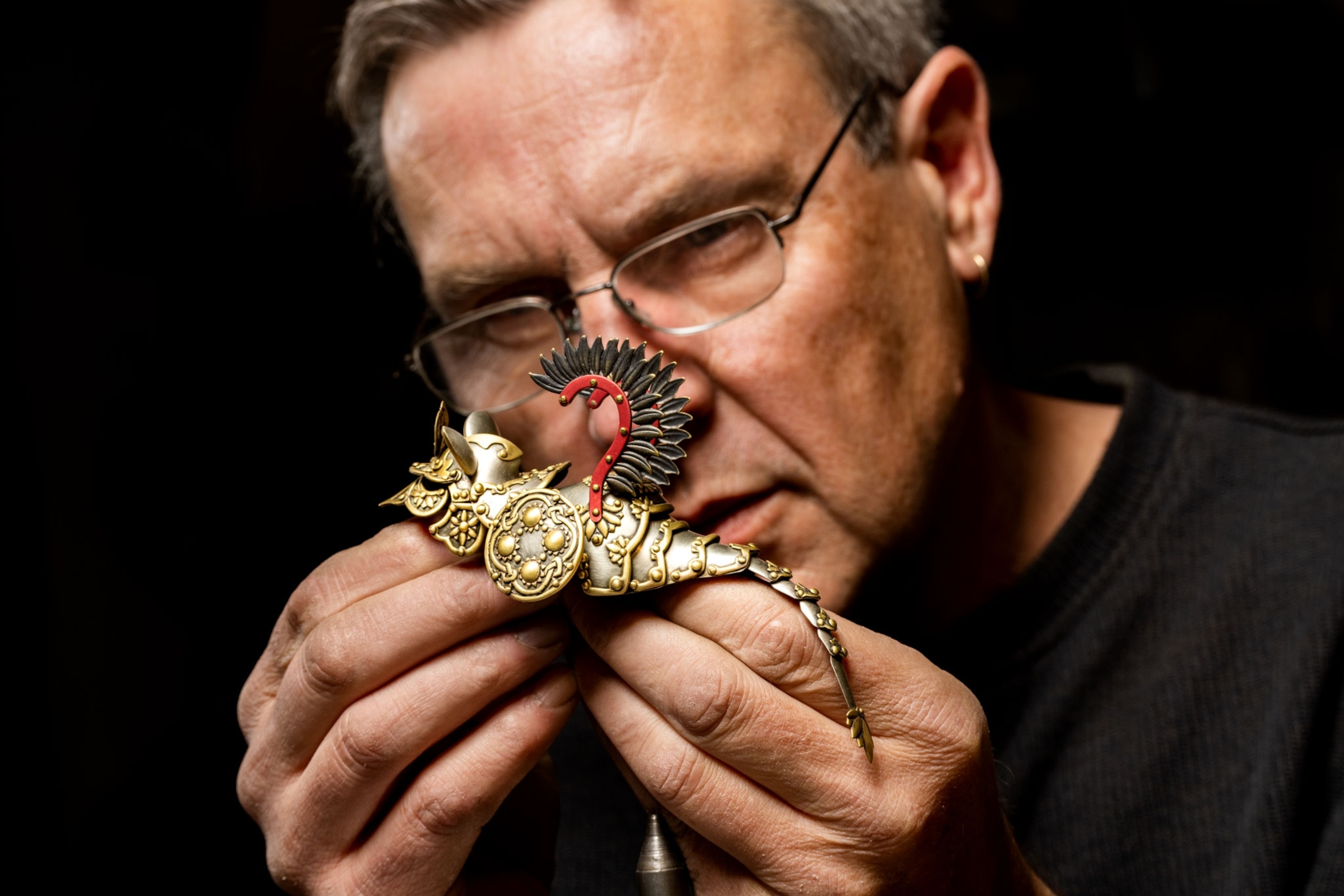 a metal artist examines a piece of art resembling mouse armor in his studio