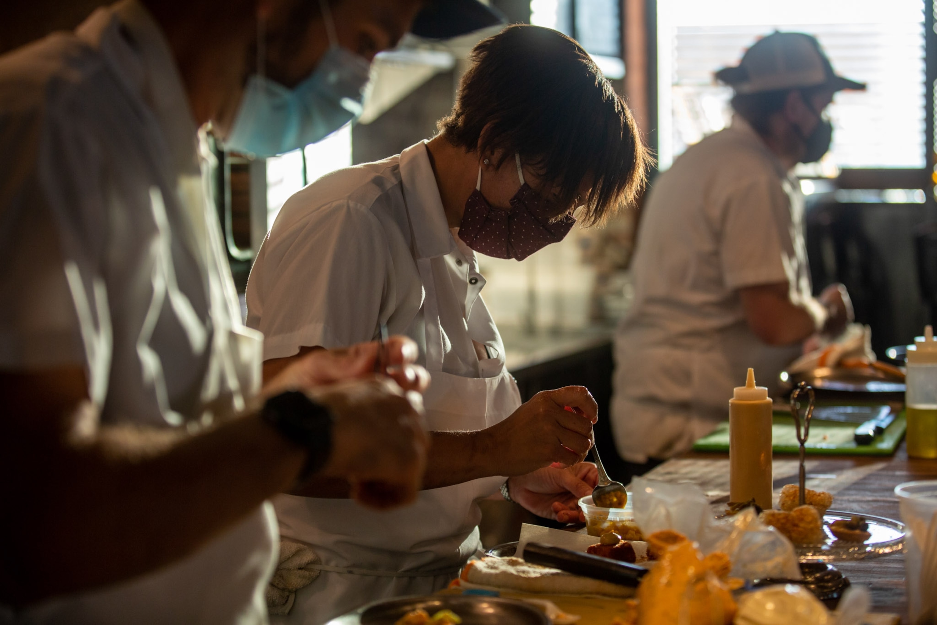 a row of chefs at a counter top preparing meals