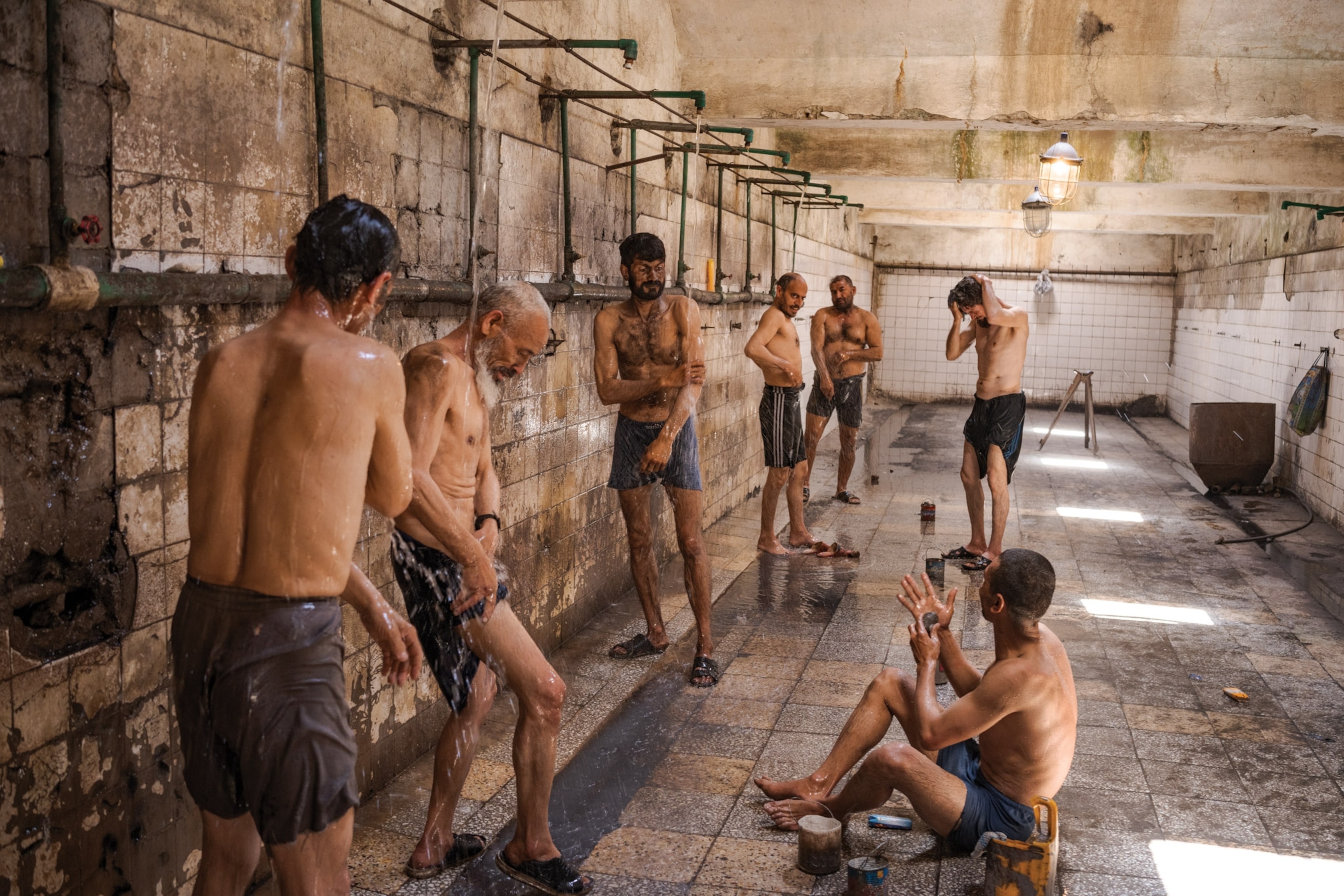 Men stand in a community shower