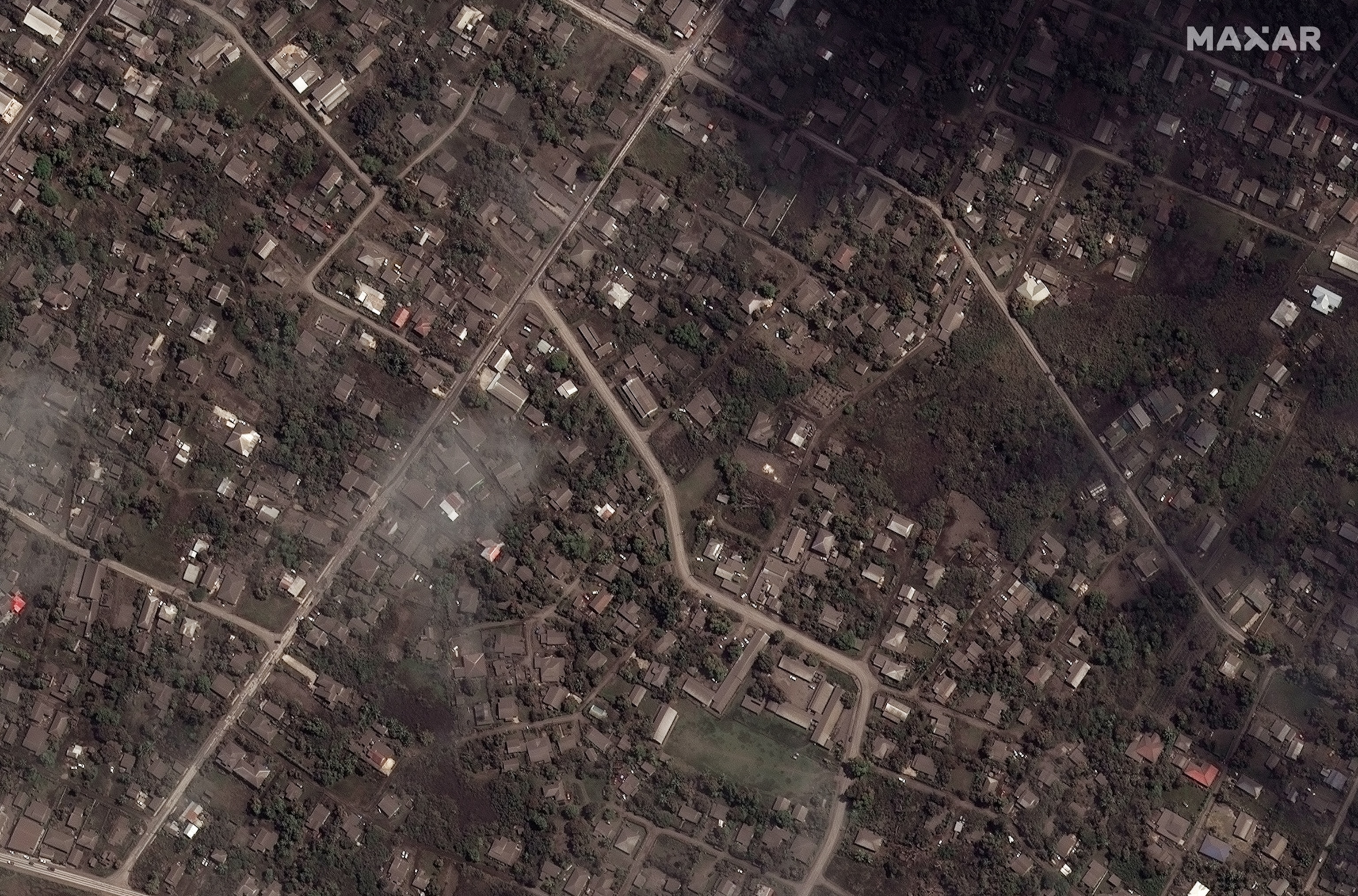 A Maxar satellite image shows homes and buildings covered in ash after main eruption.