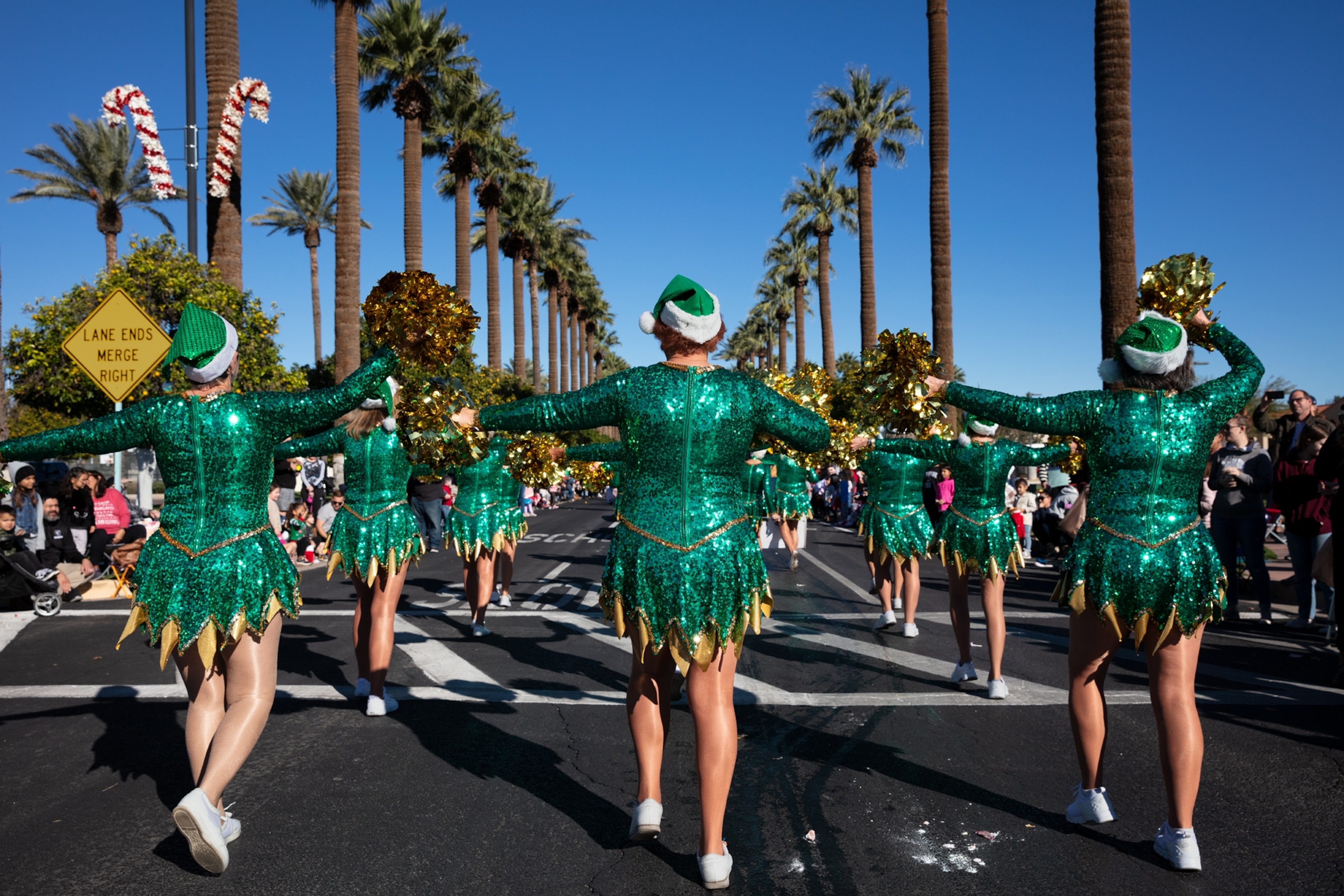 Picture of view from behind at women dressed in emerald-green short dresses and hats.