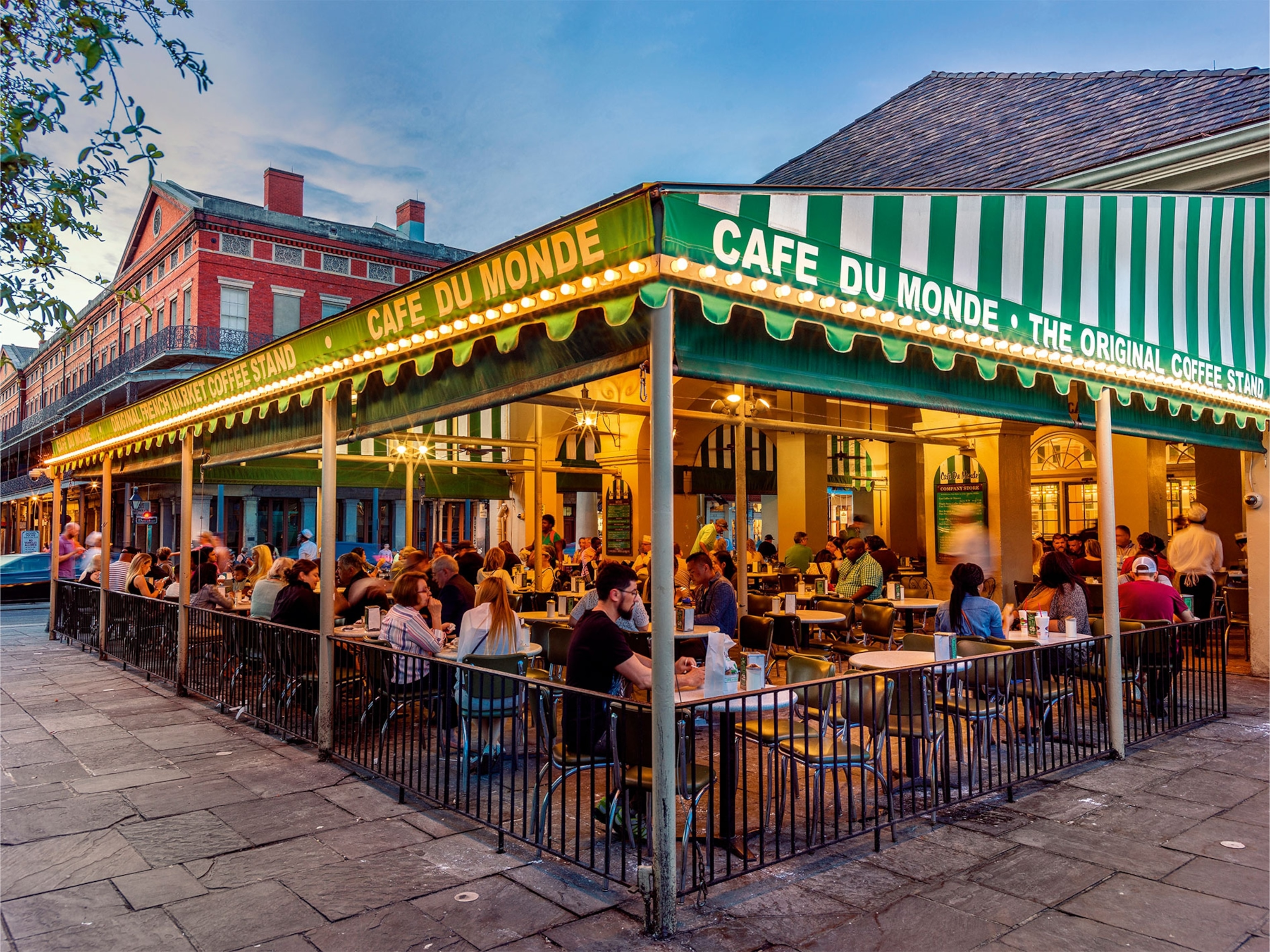 Cafe exterior at twilight, busy with diners.
