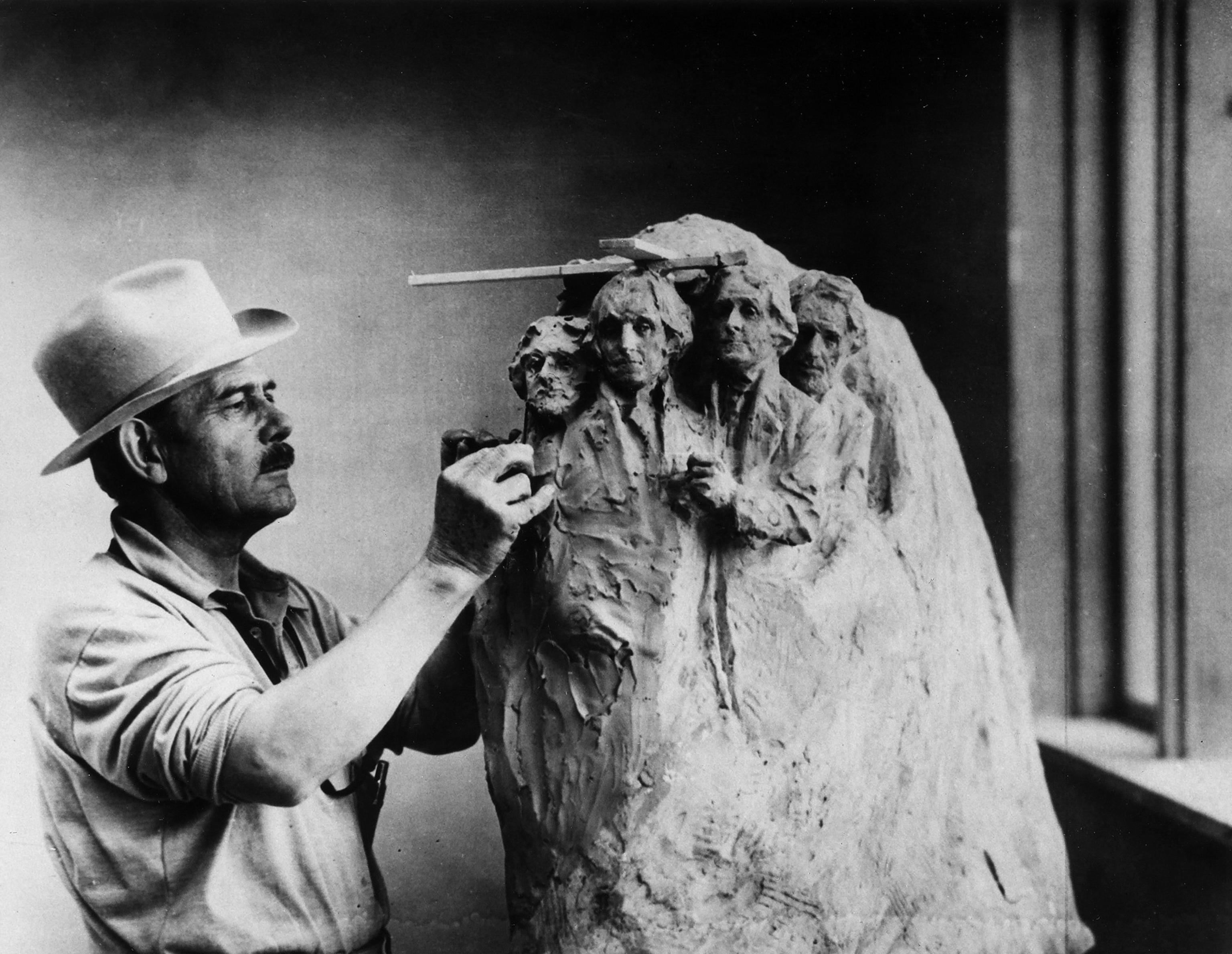 a sculptor working on a smaller draft for Mount Rushmore